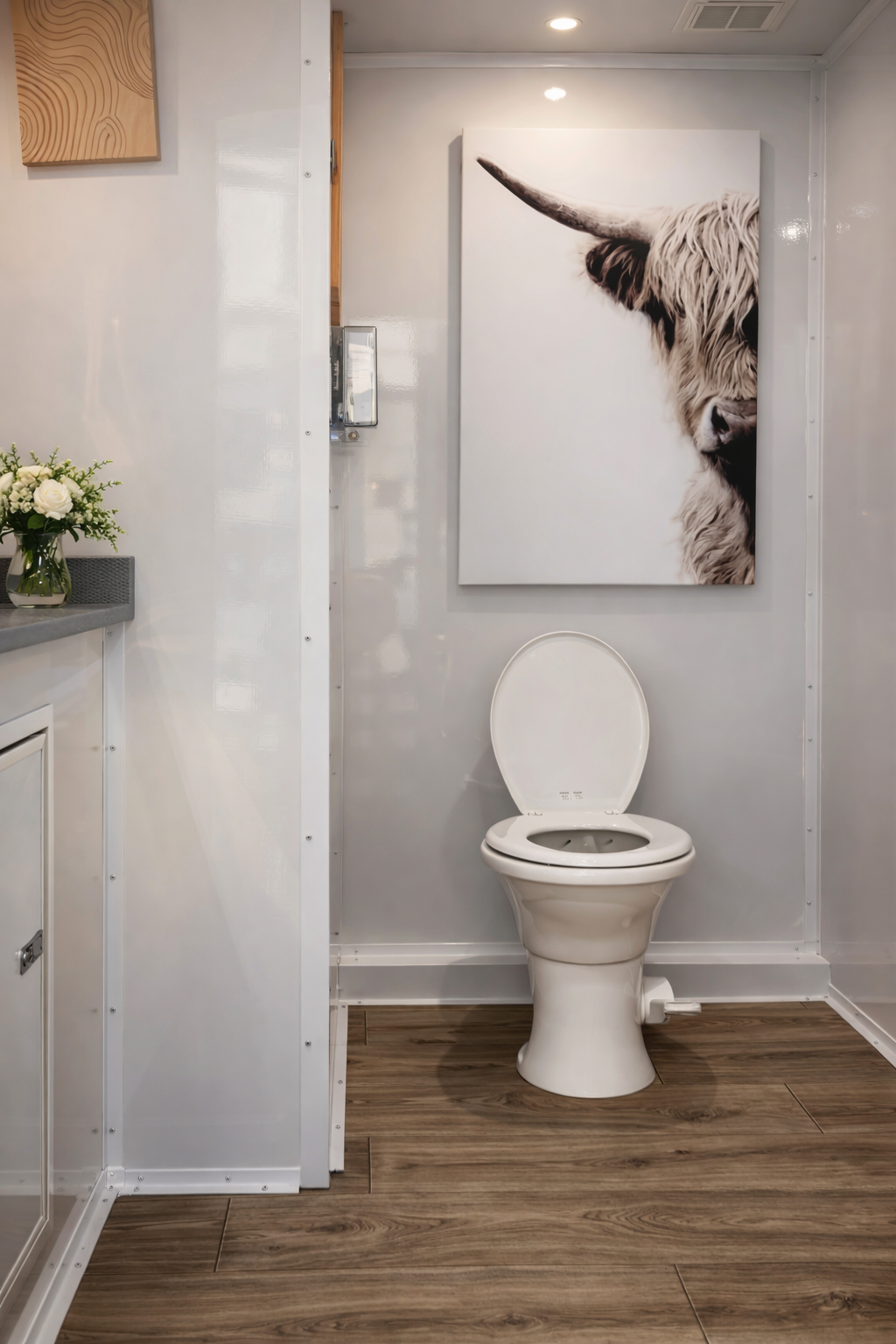 Luxury restroom trailer interior with flushing toilet, wood flooring, and modern finishes for Colorado weddings and events.