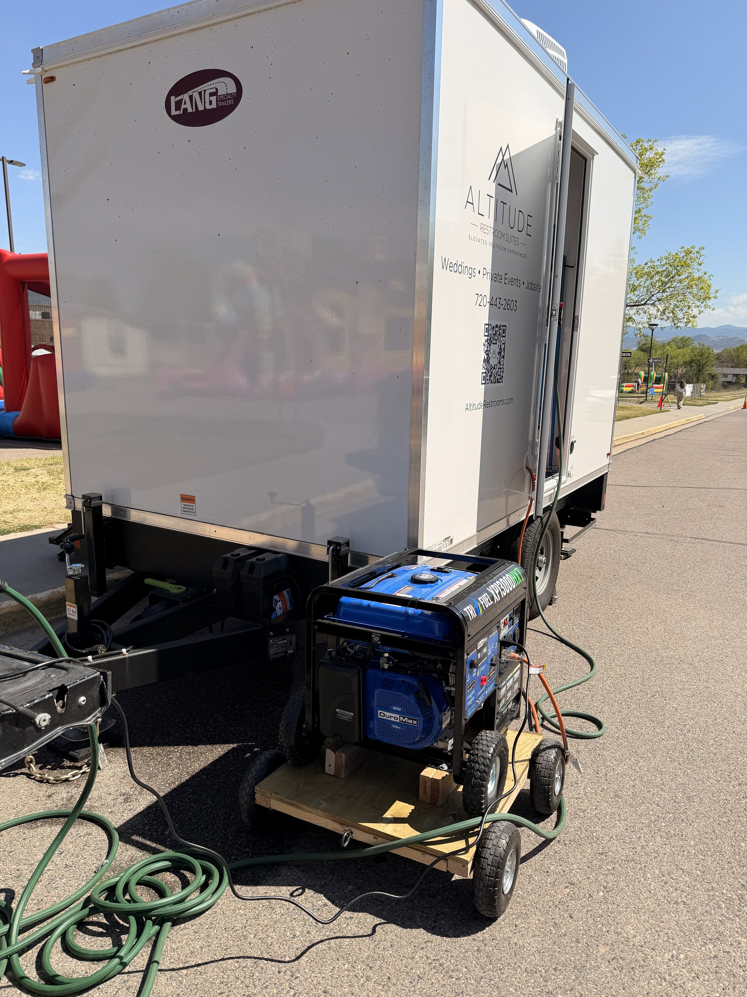 Portable generator providing electrical power to a luxury restroom trailer at an outdoor Colorado event where utility power is unavailable.