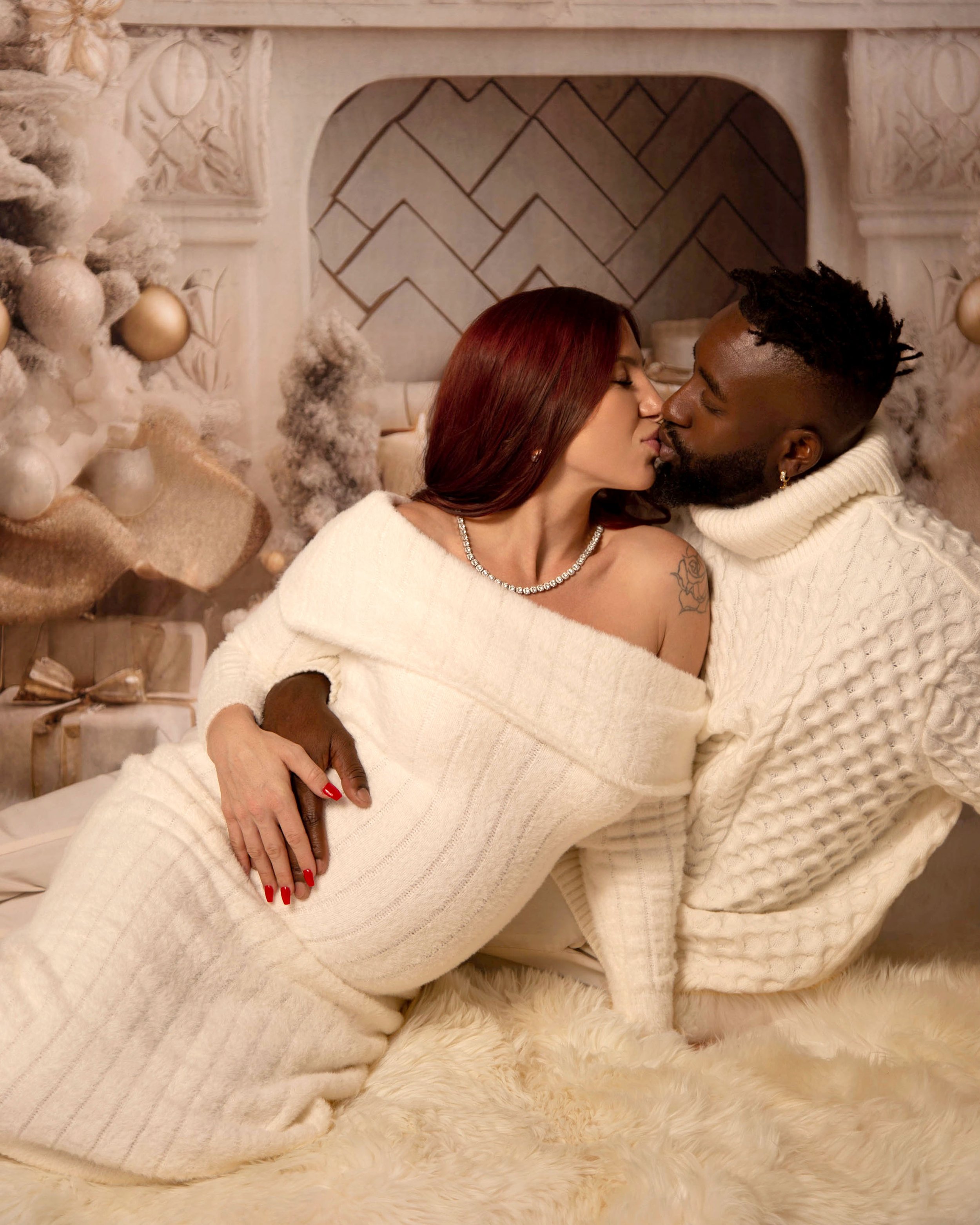 A couple sharing a kiss in a cozy, decorated space with Christmas tree and presents.