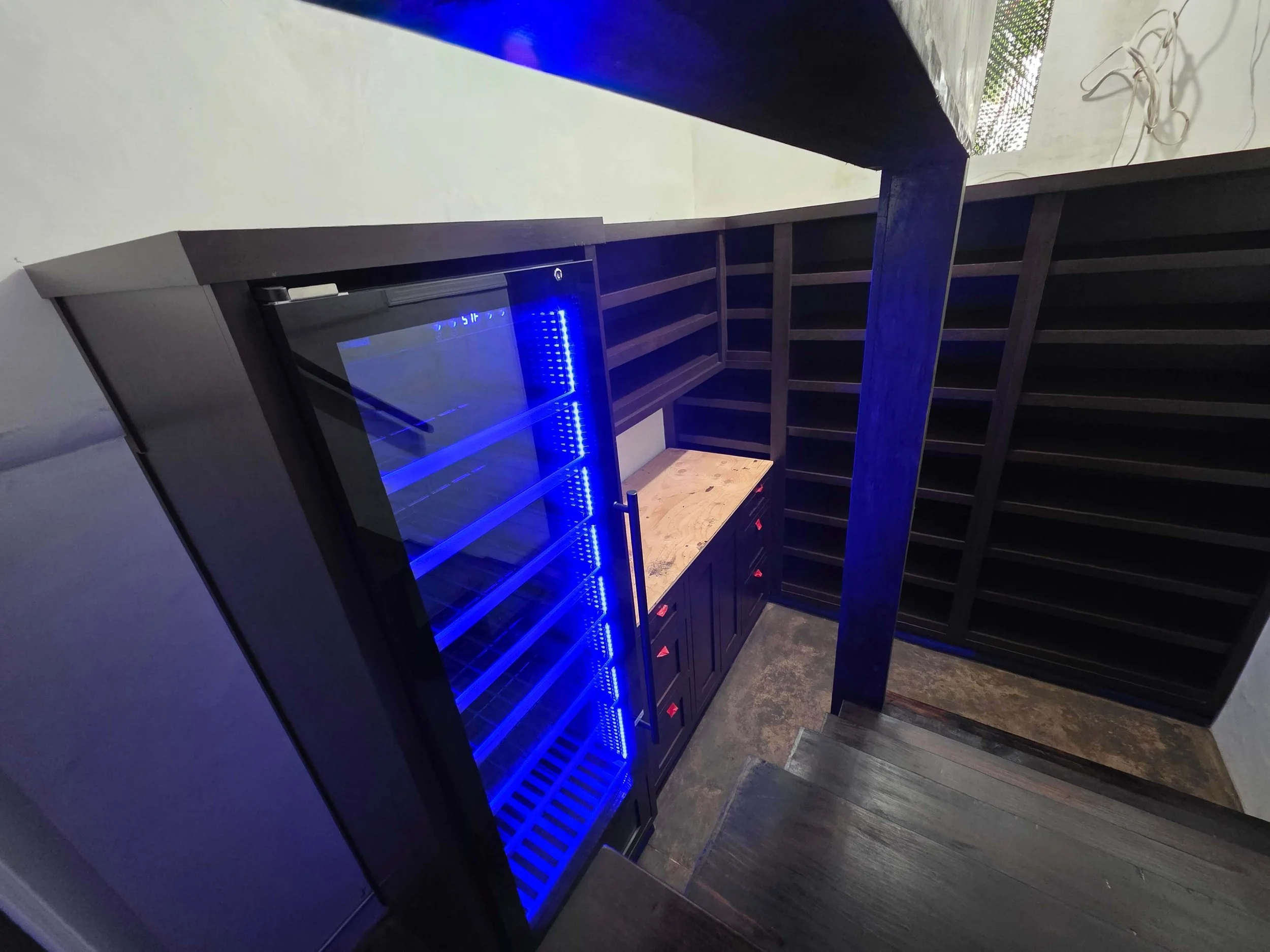 Custom wine cellar with changing color light. Large wine fridge. Granite counter tops. Dark wood.