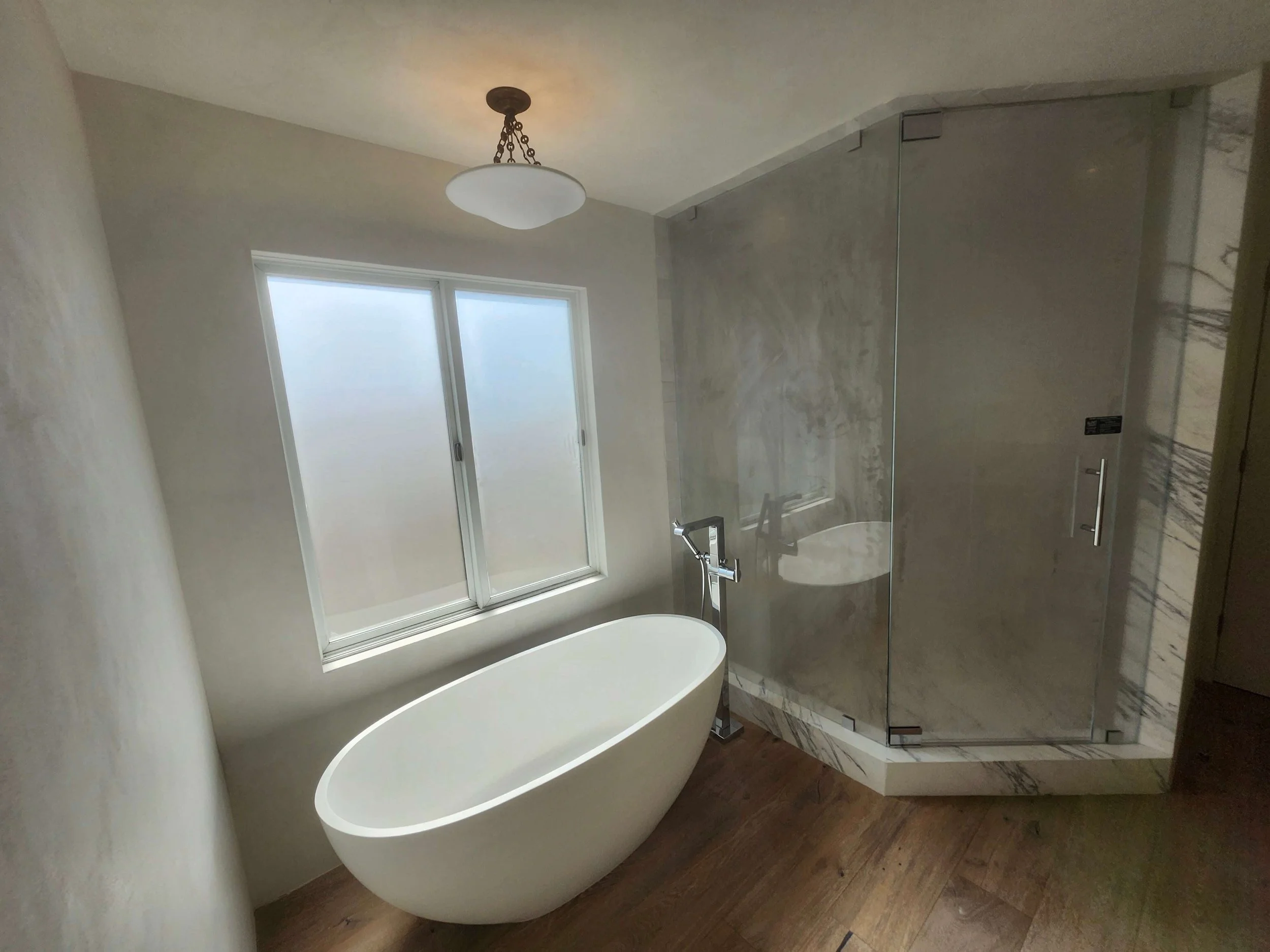 Bathroom renovation. New stand alone bathtub with external faucet. Granite and glass large shower. Wood floors.