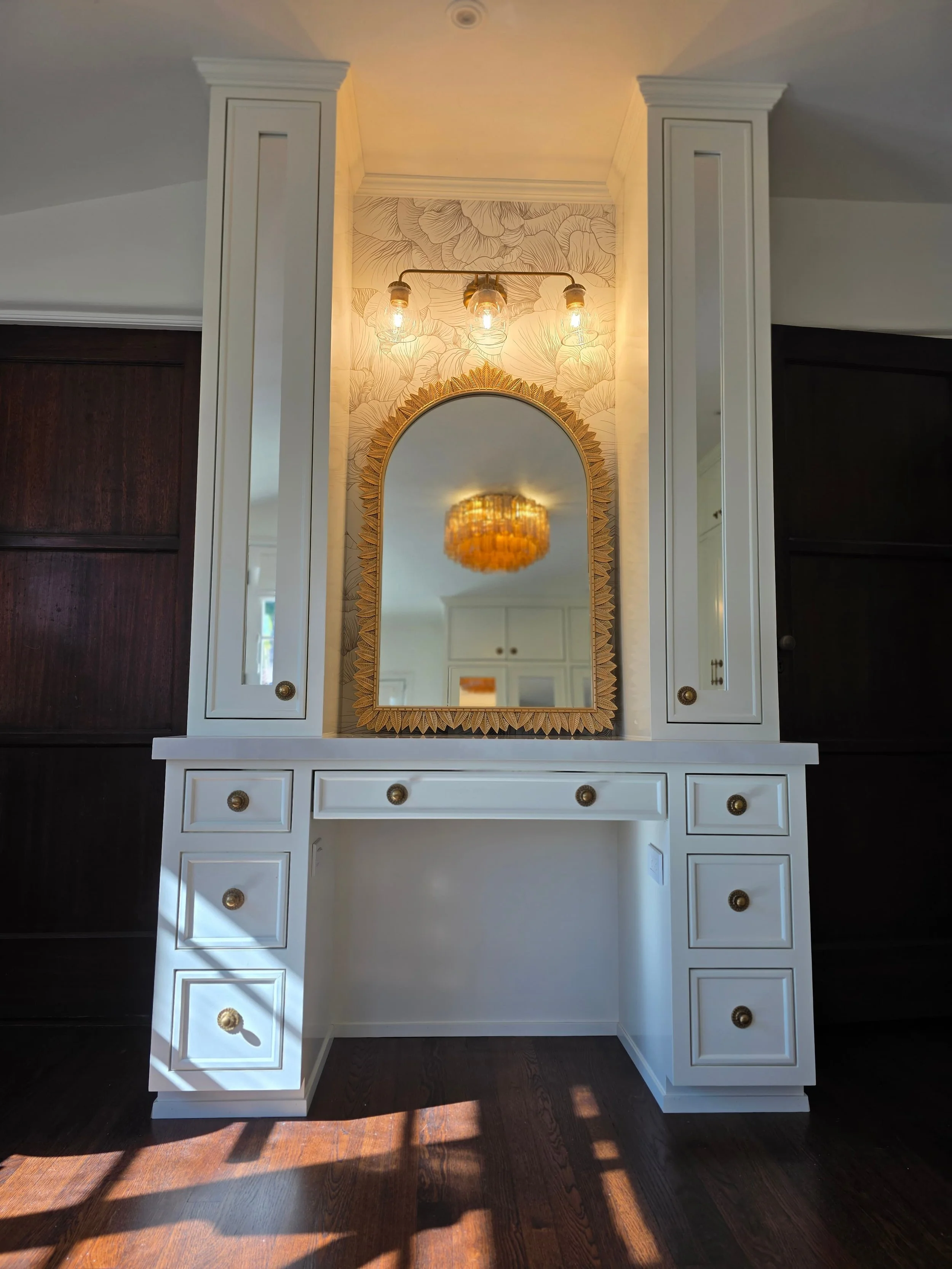 Luxury vintage closet done in white and gold. Mirrors reflect light. Wood work.