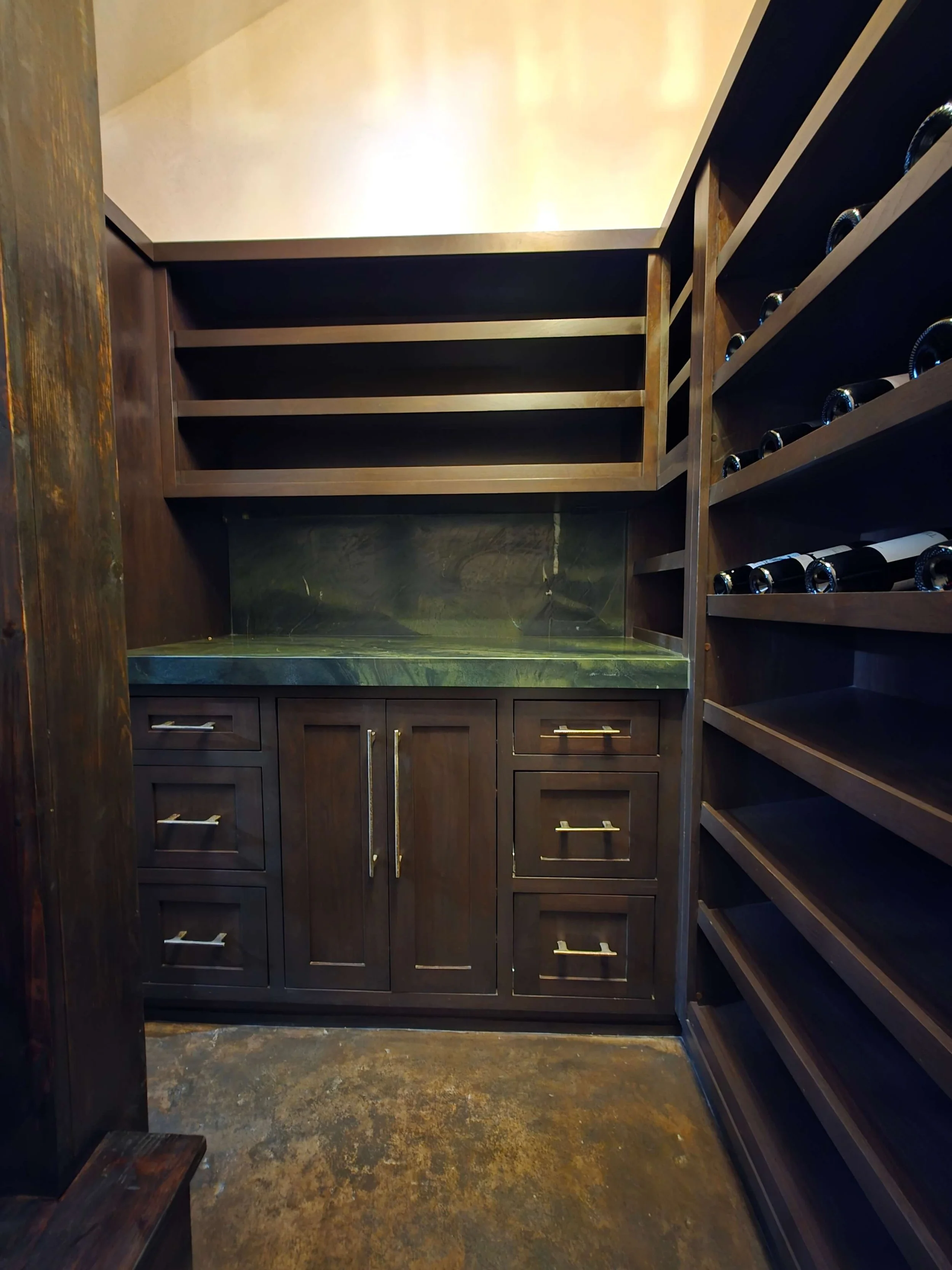 Custom wine cellar with dark wood work, proper ventilation, and granite counter tops