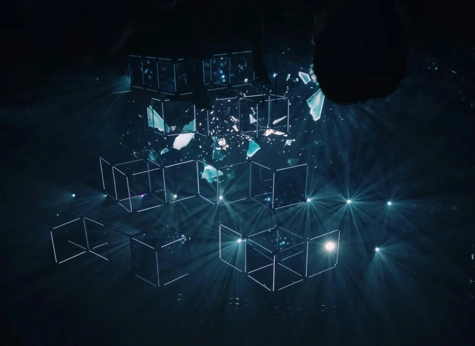 Lichtinstallation mit leuchtenden rechteckigen Rahmen und reflektierenden Fragmenten in einer dunklen Umgebung.