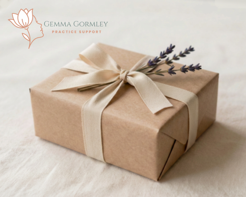 A gift wrapped in brown paper with a cream-colored ribbon bow, decorated with a sprig of lavender, and the logo of Gemma Gormley Practice Support in the top left corner.
