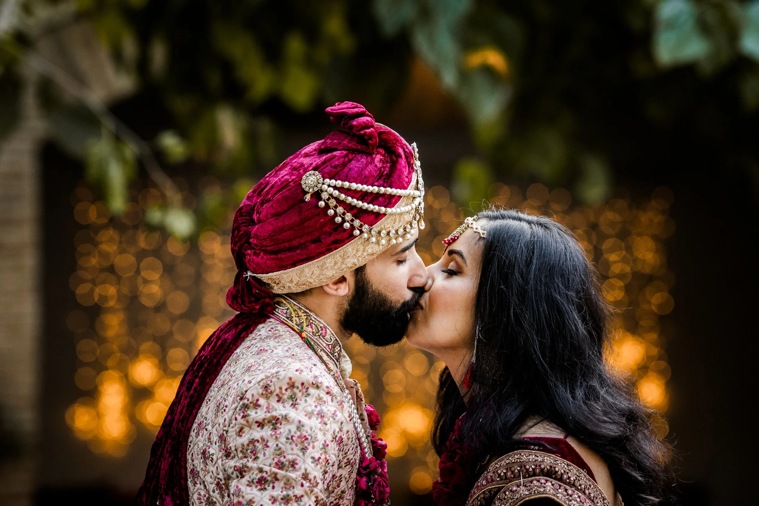 A couple dressed in traditional Indian wedding attire sharing a kiss during their destination indian wedding at Casa Almanita , Barcelona