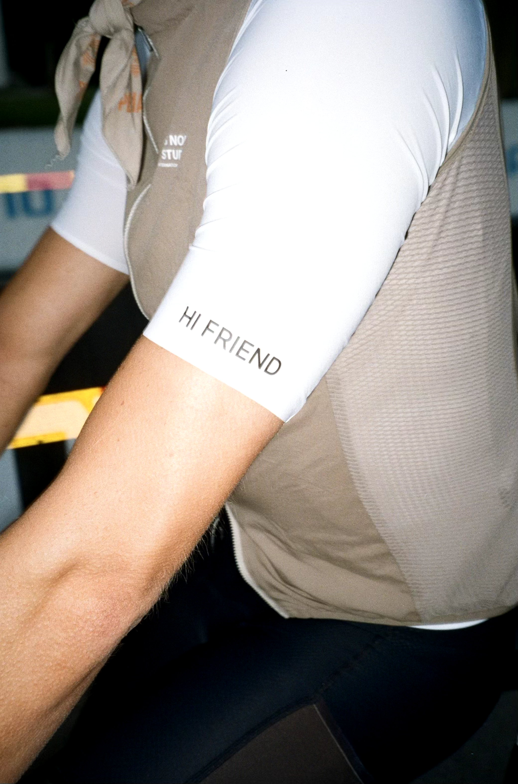 Close-up of a person wearing a beige and white short-sleeve shirt with the words "HI FRIEND" on the sleeve.