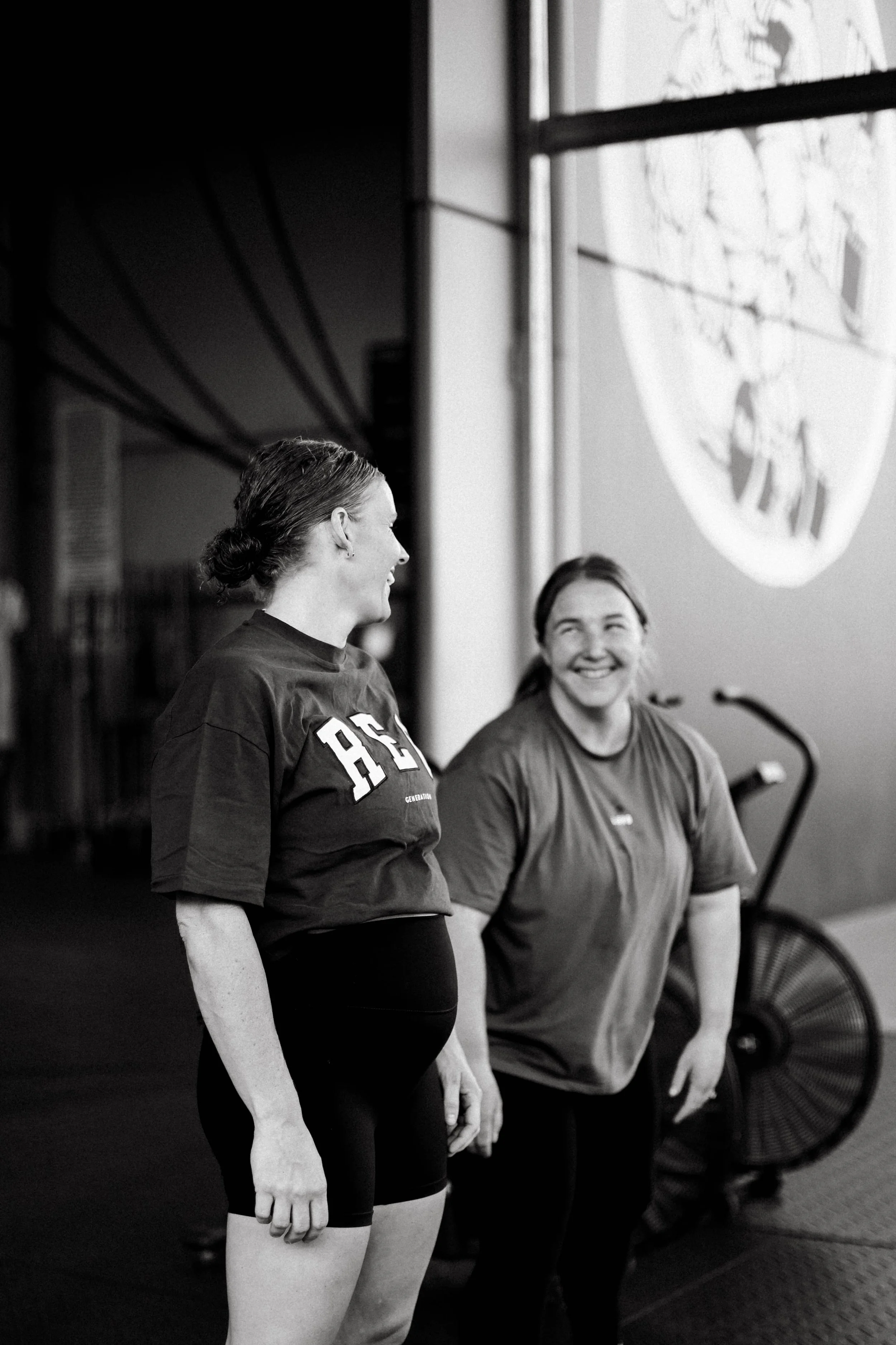 Katelyn (pregnant) and Beth are smiling and engaging in conversation outside of CrossFit Dubbo.