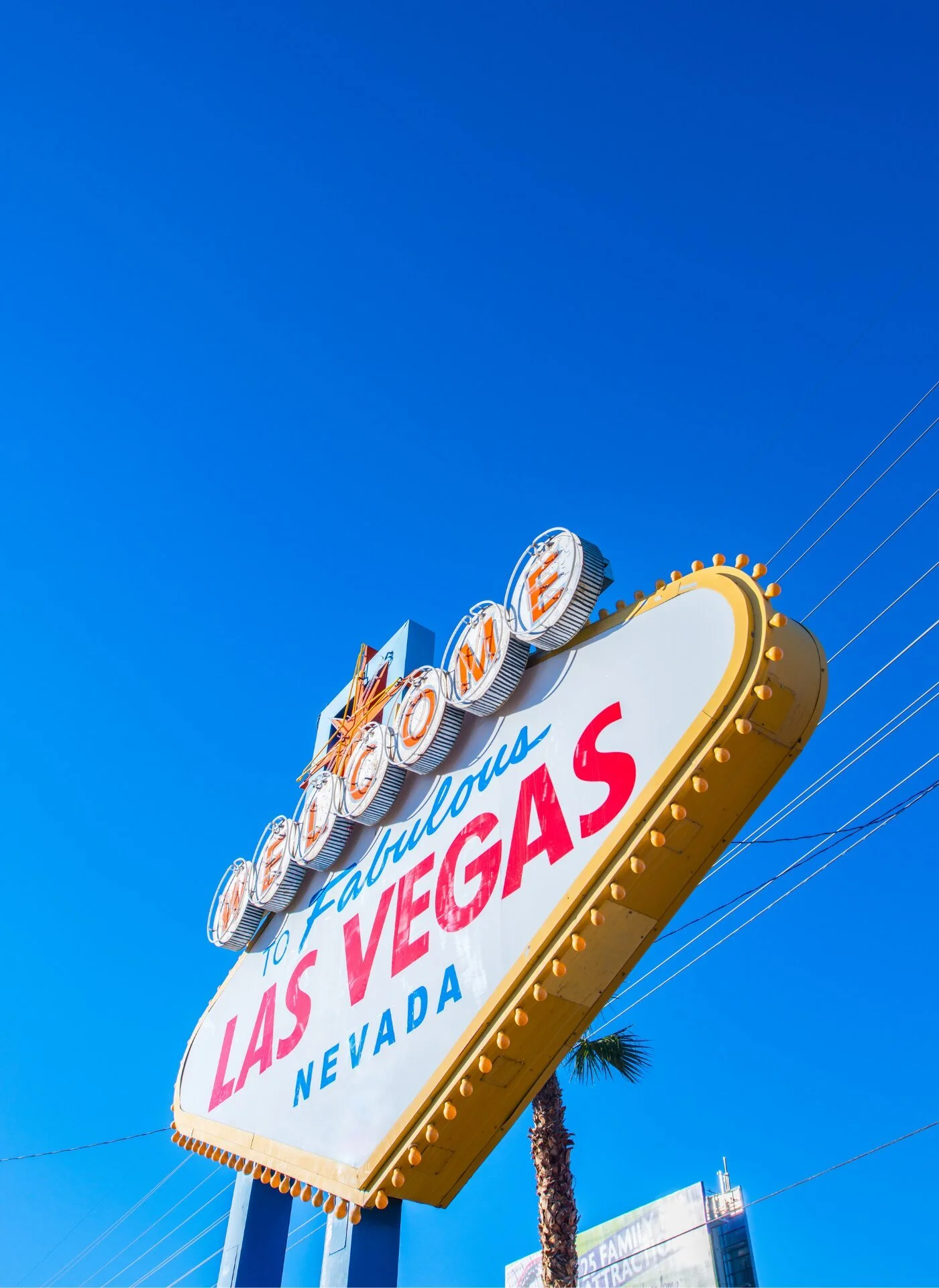 The iconic welcome sign for Las Vegas, Nevada, with bright lights and a clear blue sky in the background.