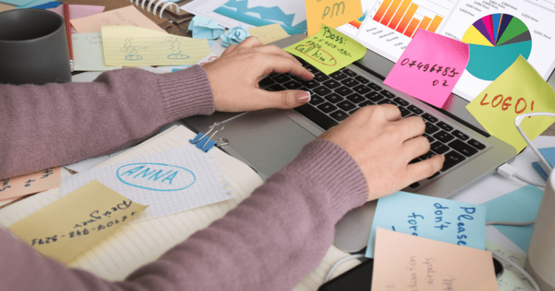 image of cluutered desk with person using laptop and trying to focus