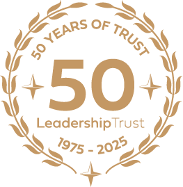 Gold and black circular emblem celebrating 50 years of trust, with text '50 Years of Trust Leadership Trust 1975-2025' and decorative laurel branches.