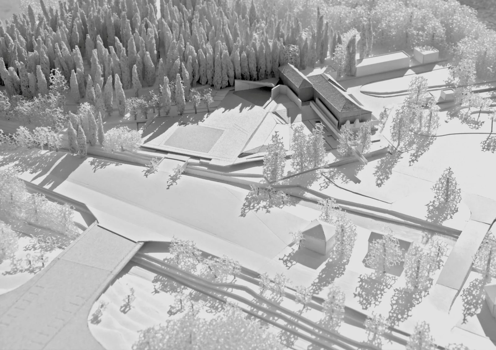 Architectural model of a building complex surrounded by trees, with a focus on modern design elements and outdoor spaces, all in a monochromatic color scheme.