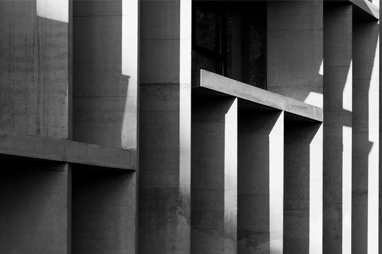 Black and white photograph of modern architectural concrete building with vertical columns and shadows.
