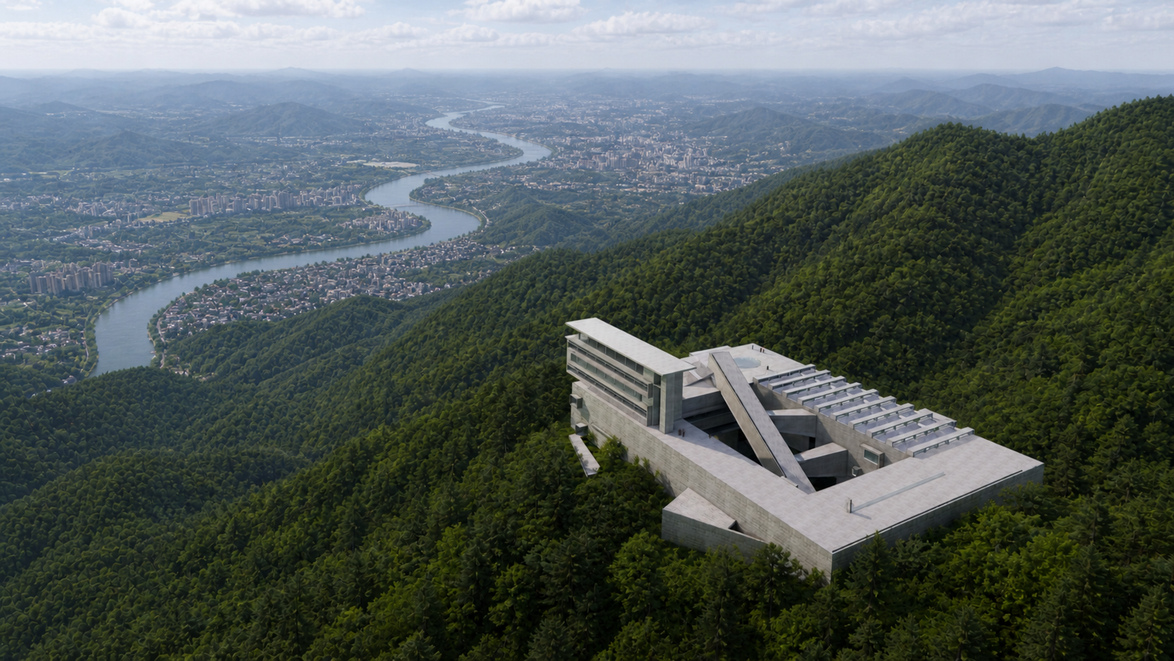 Modern building on a hillside overlooking a river and cityscape in the distance, surrounded by lush green mountains.
