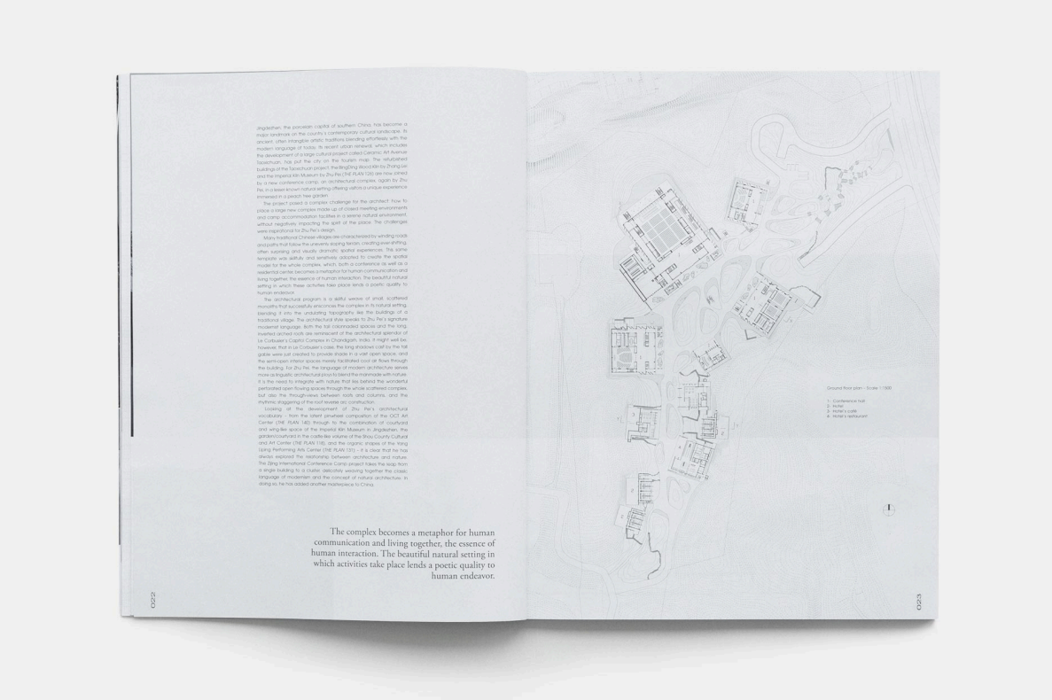 Open book showing a detailed architectural blueprint of a complex with multiple buildings and landscaping features, along with a page of text describing the project.