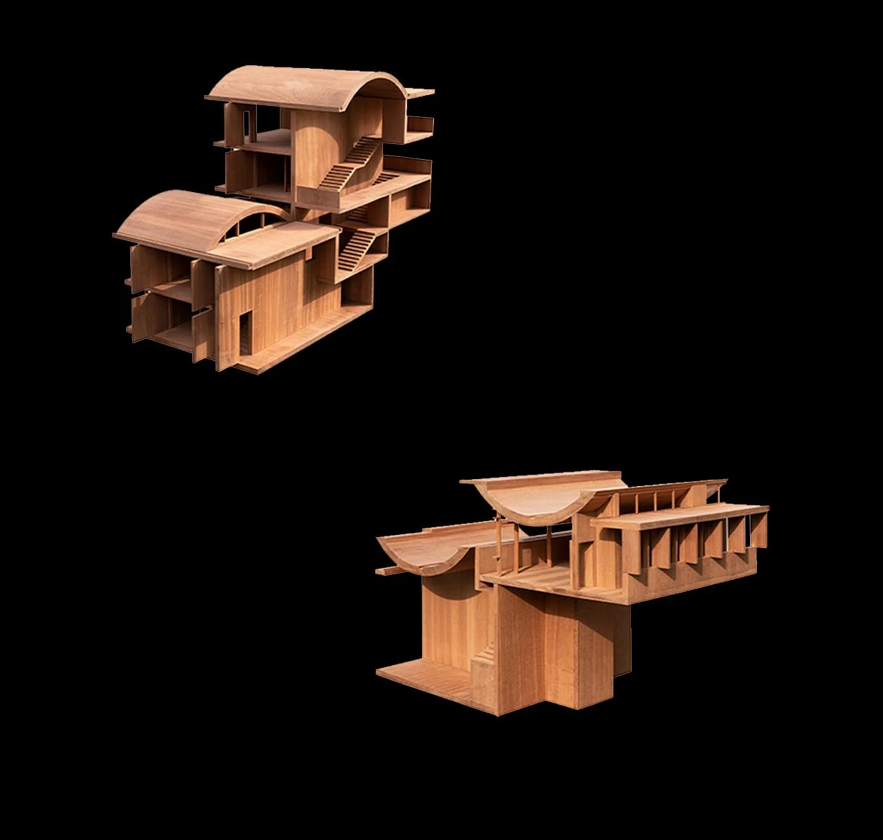 Two wooden architectural models with complex, curved rooftop designs set against a black background.