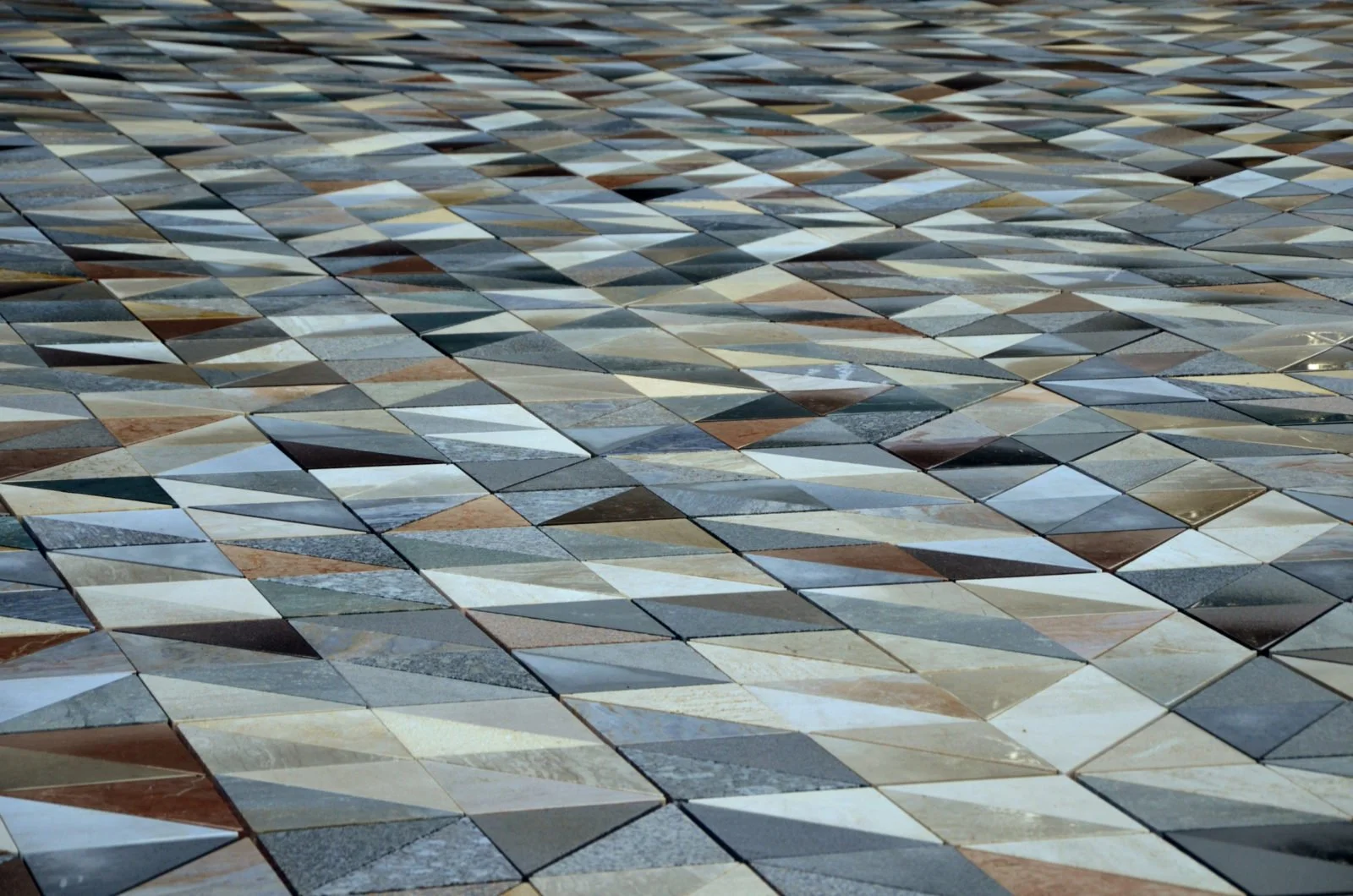 Close-up view of a mosaic floor composed of variously colored and shaped tiles, creating a geometric pattern.