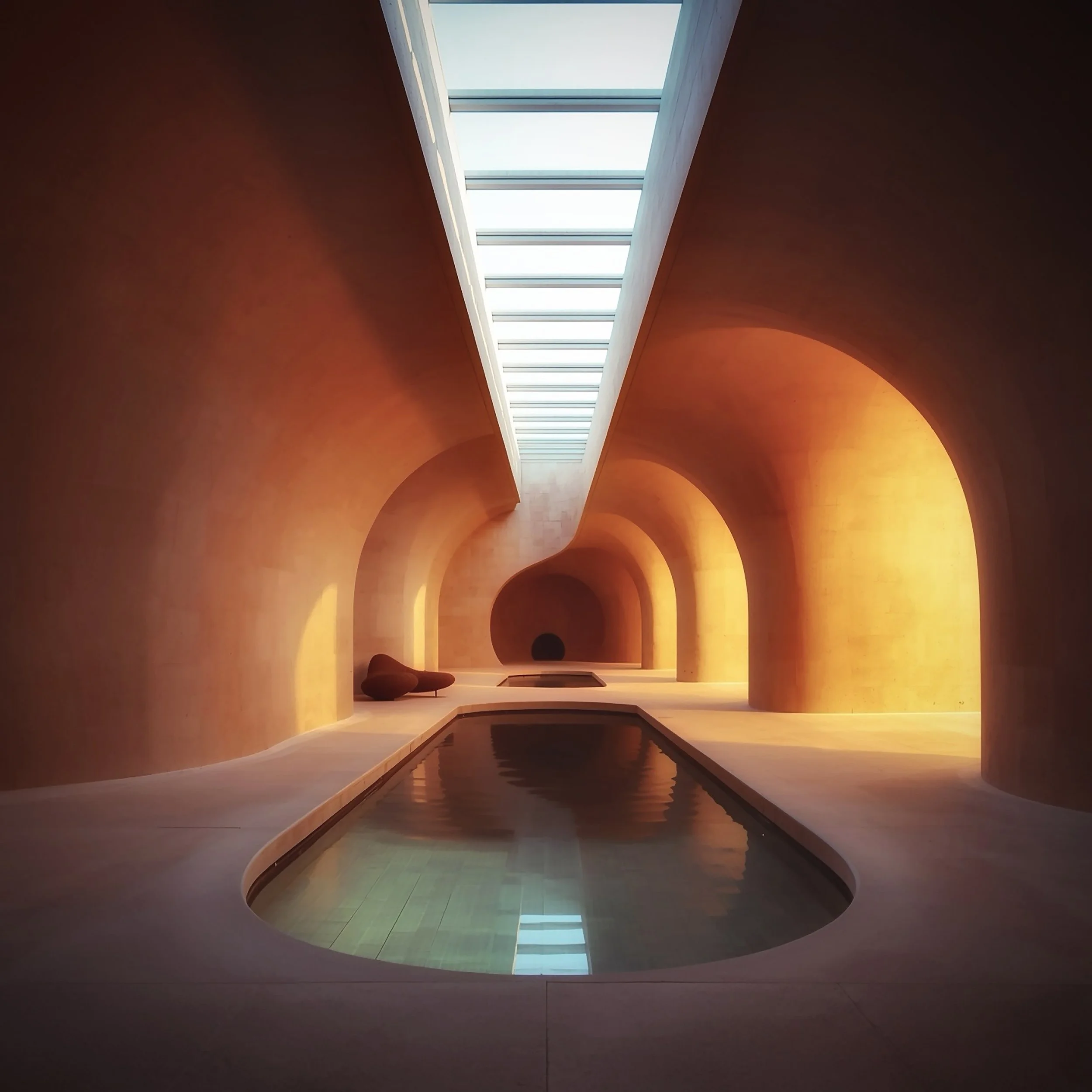 Interior view of a building with curved orange walls, green flooring, and a skylight ceiling