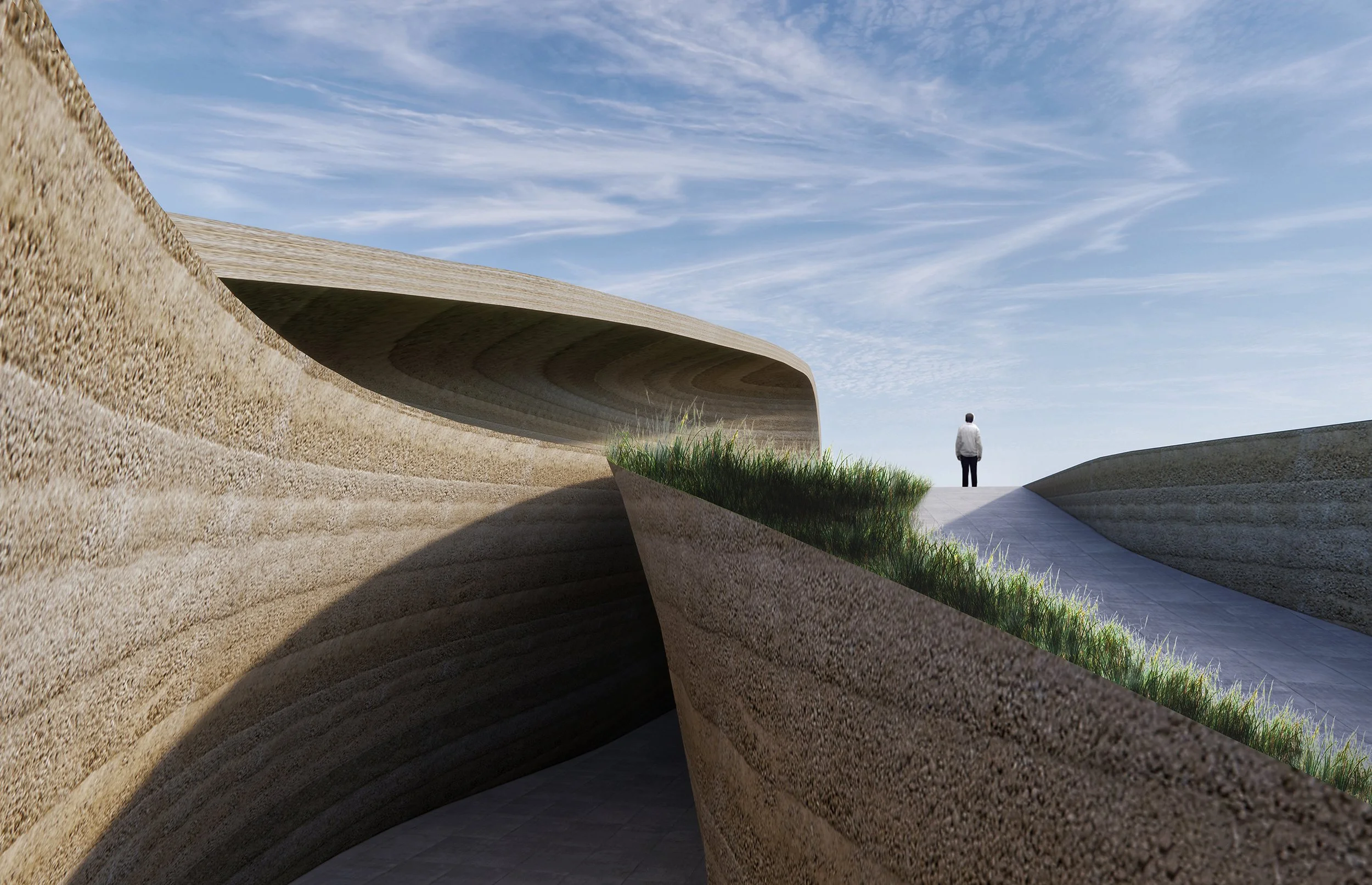 A person standing outdoors near modern, curved architectural structures made of textured concrete, with a walkway and green grass, under a partly cloudy sky.