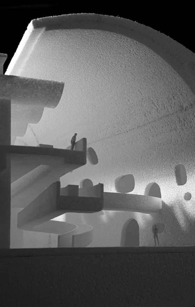 Interior view of an abstract architectural space with curved and layered structures, circular openings, and small human figures.