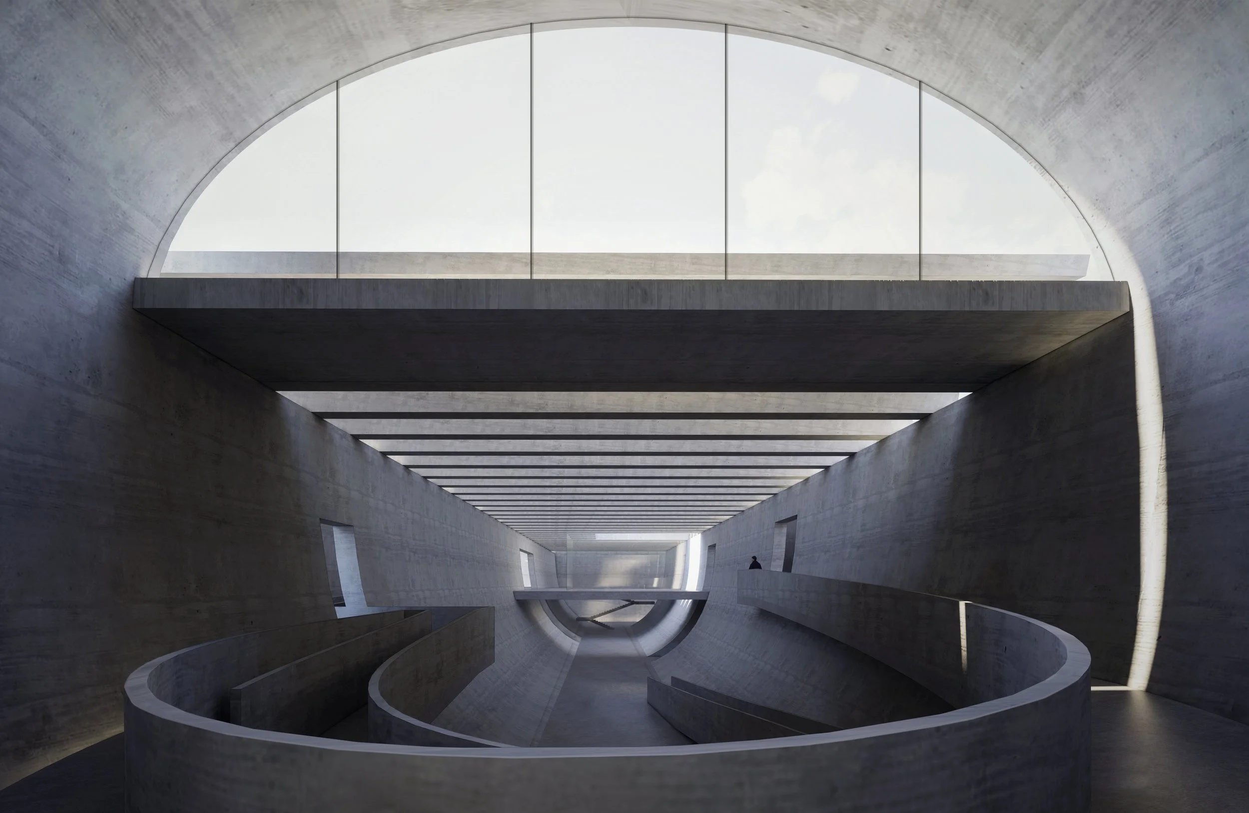 View of an indoor architectural space with concrete walls and ceiling, featuring a large, arched window or opening at the top, allowing natural light to illuminate the area. The design includes a walkway with a spiral-shaped railing on the lower level.