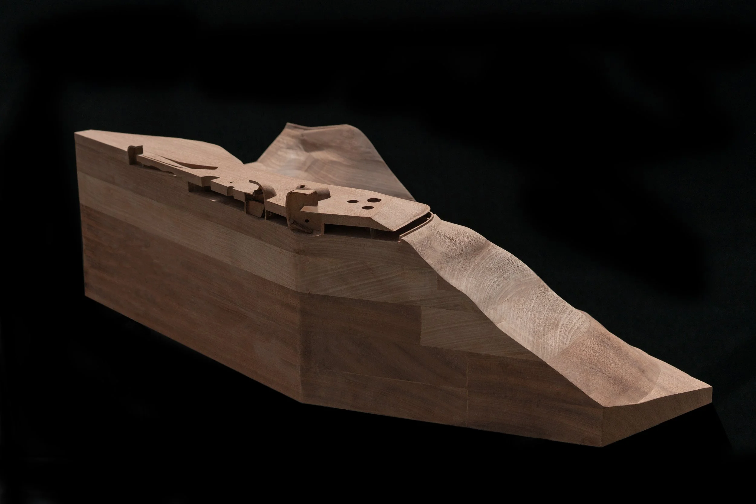 A detailed wooden model of a ship, showcasing the hull and deck structure, set against a black background.