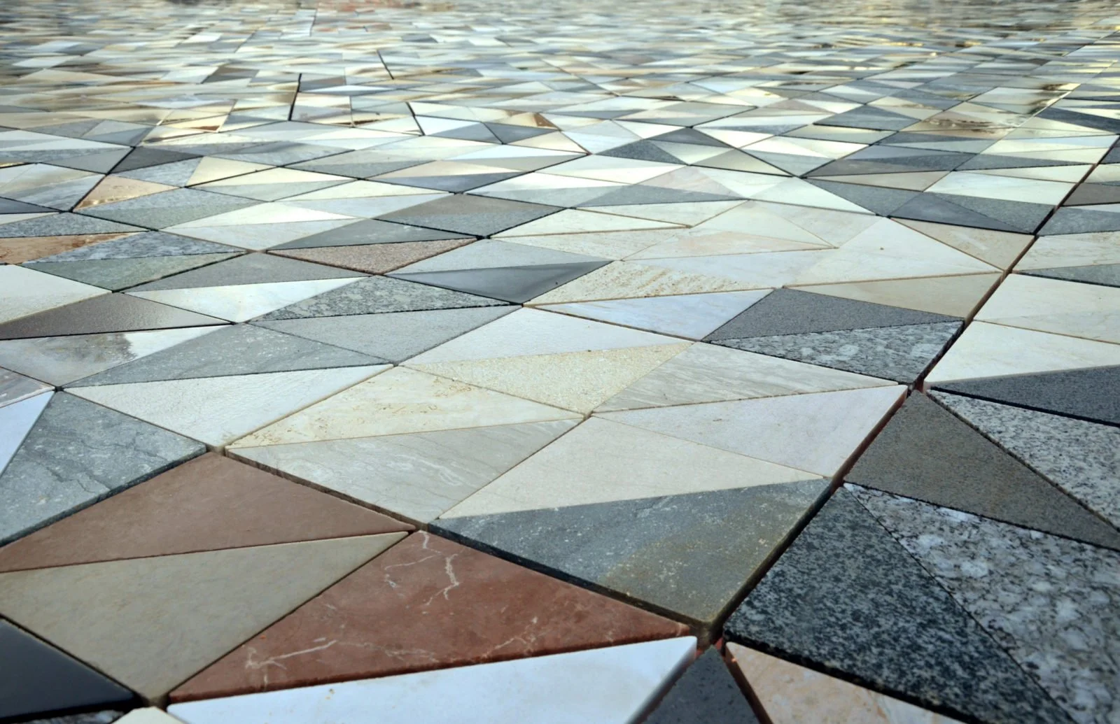 Close-up of a mosaic tiled floor with various colored triangular and diamond-shaped tiles.
