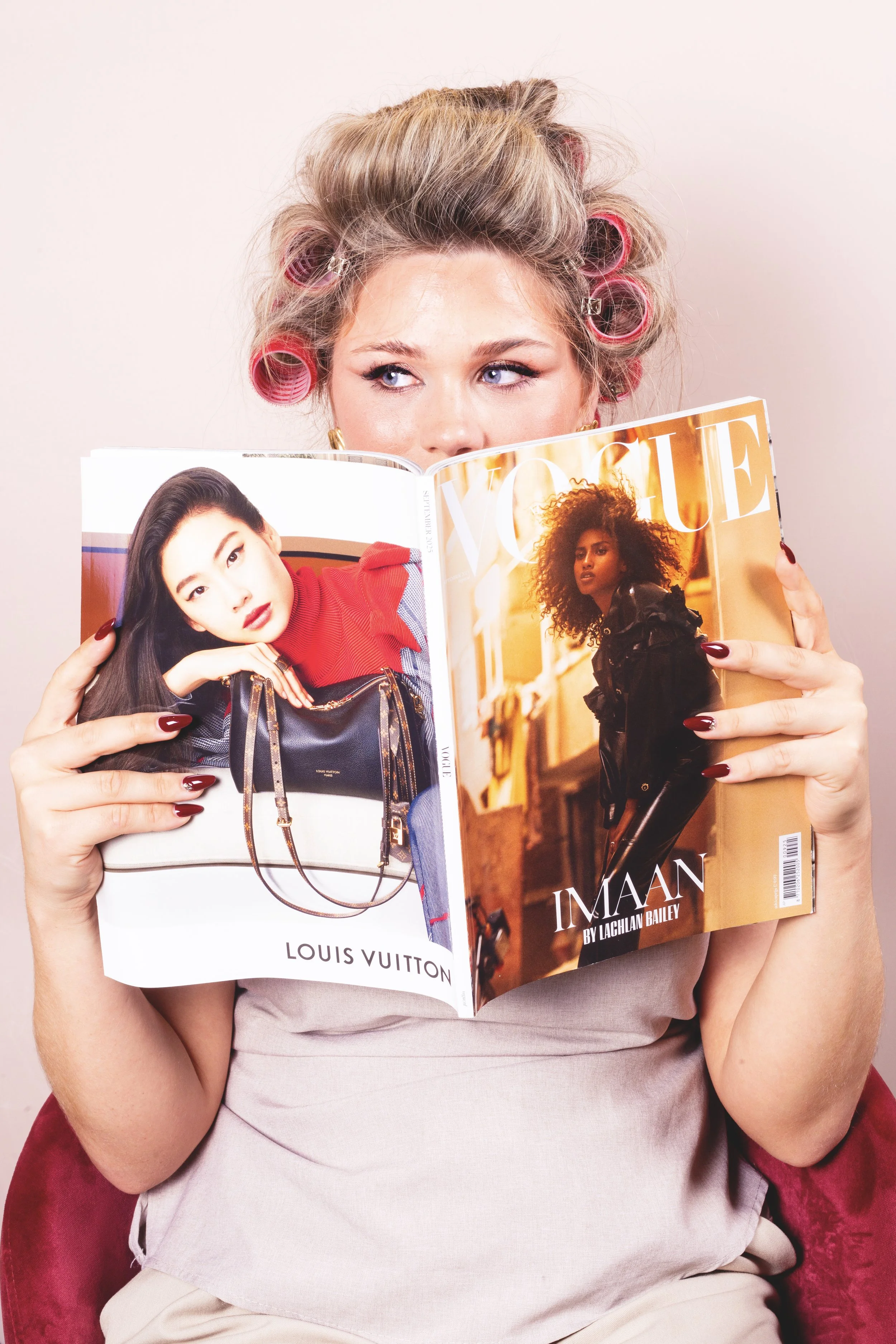 vrouw met krulspelden die boven magazine uitkijkt voor shoot door atelier soufflé