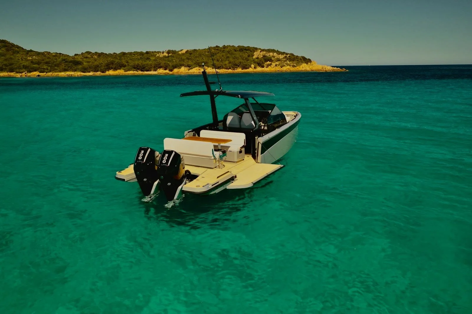 Una barca moderna con motori fuoribordo su acque turchesi, con un'isola verde sullo sfondo.