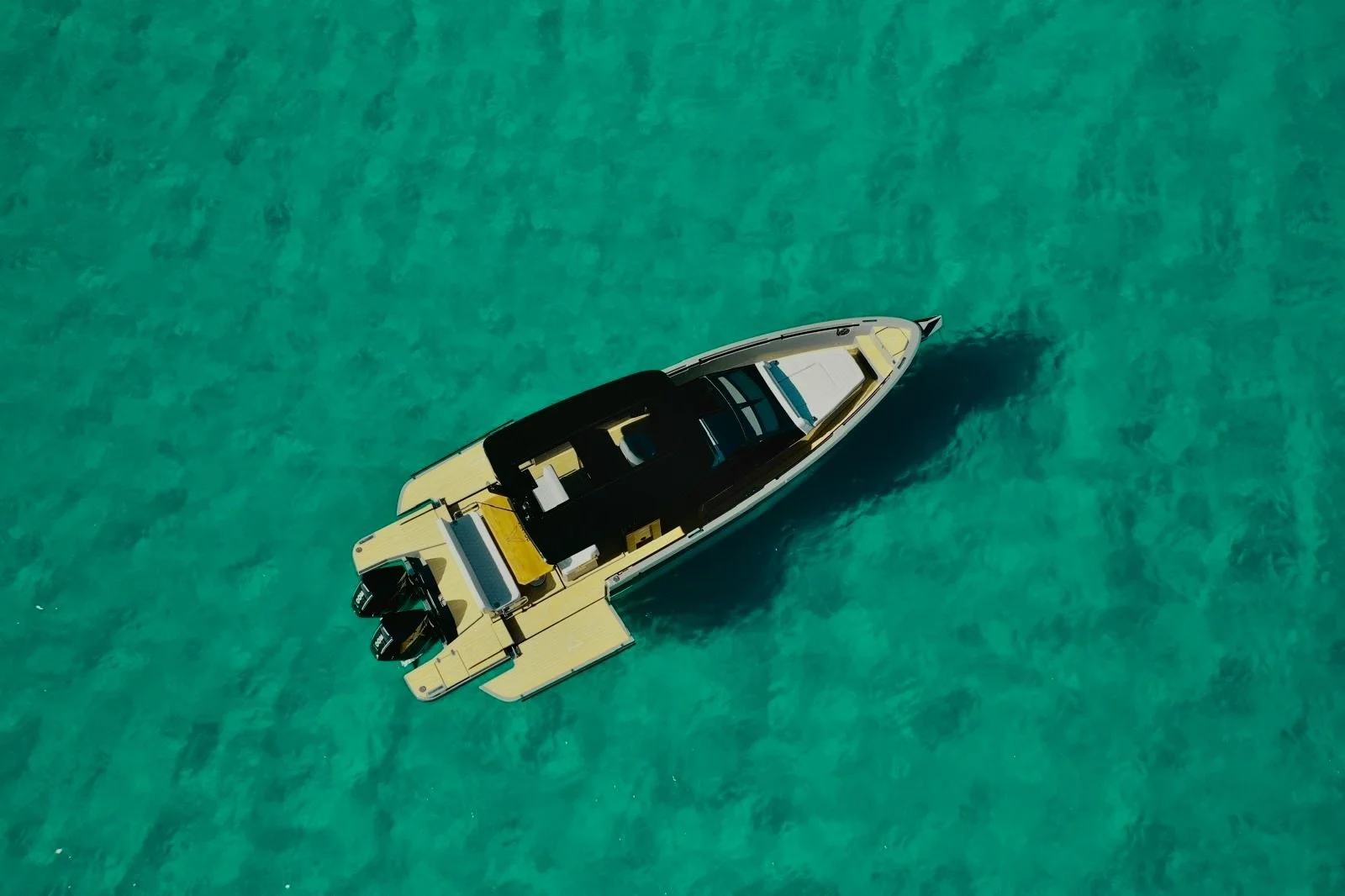 Immagine aerea di uno yacht moderno in acque cristalline turchesi.