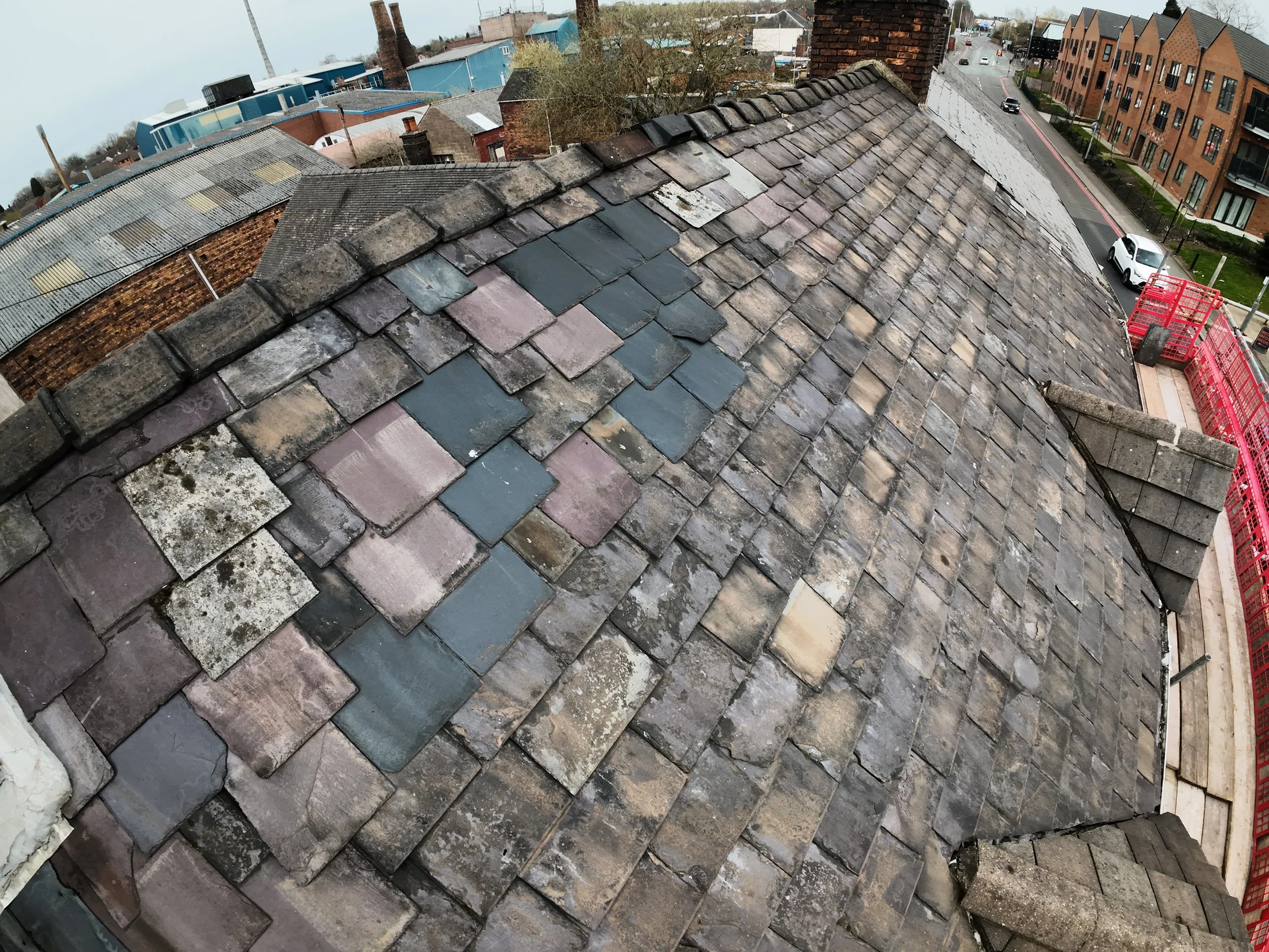 Roof with mismatched replacement tiles and poor repair work seen during a drone inspection.