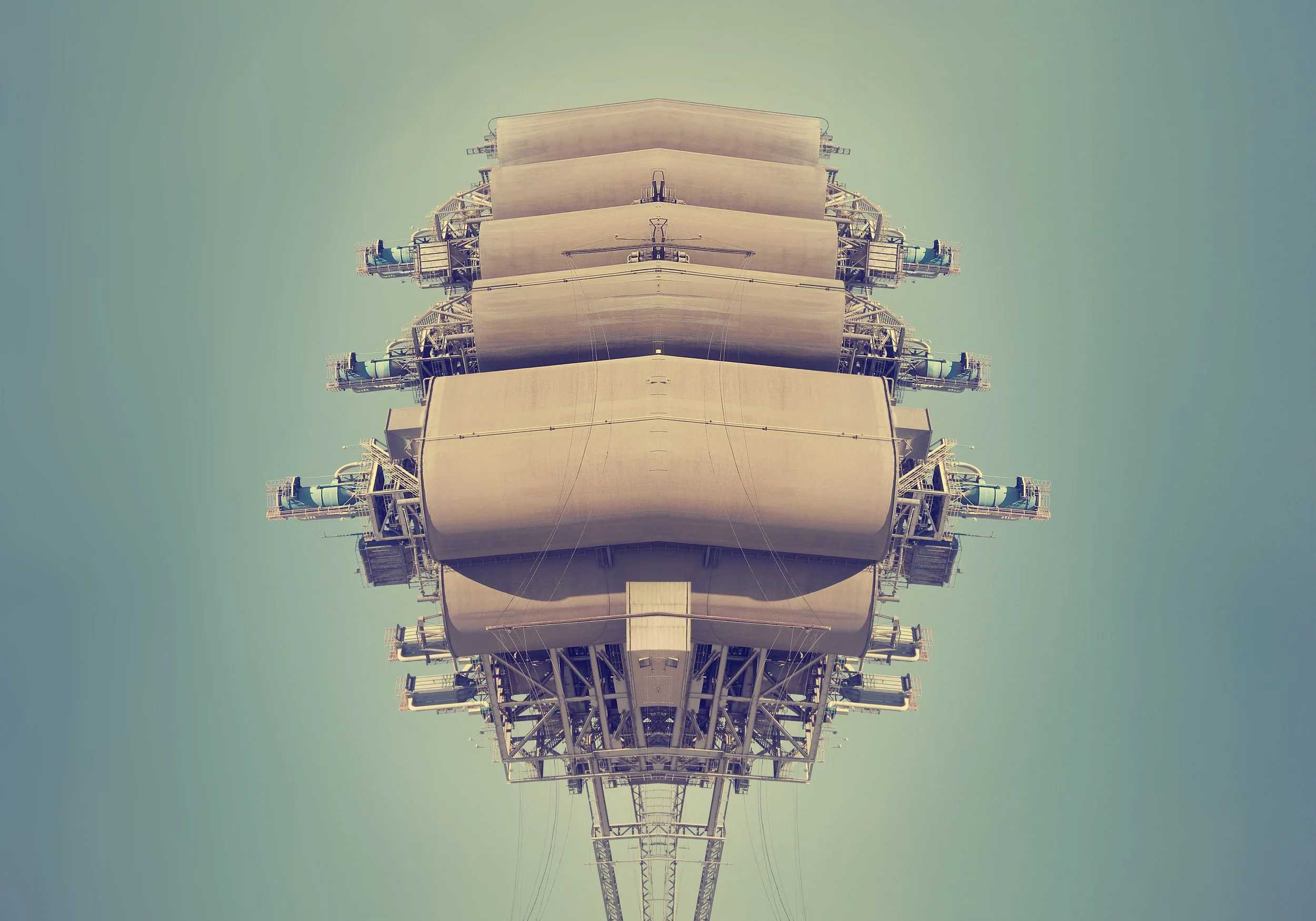 A mirrored, symmetrical view of a large industrial structure or tower against a clear sky.