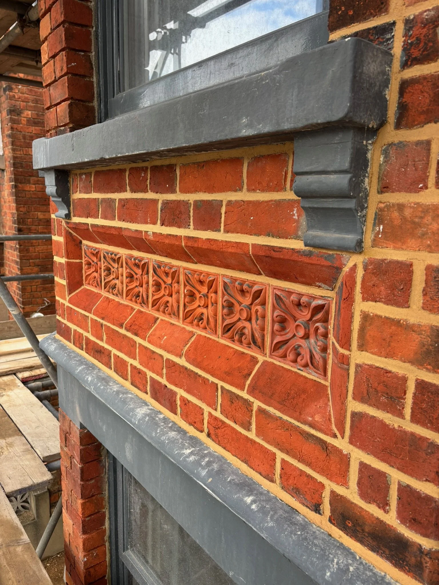 Close-up of a Victorian brick wall with a decorative brick panel and a gray stone window ledge, restored by the Bedford Victorian Restoration team.
