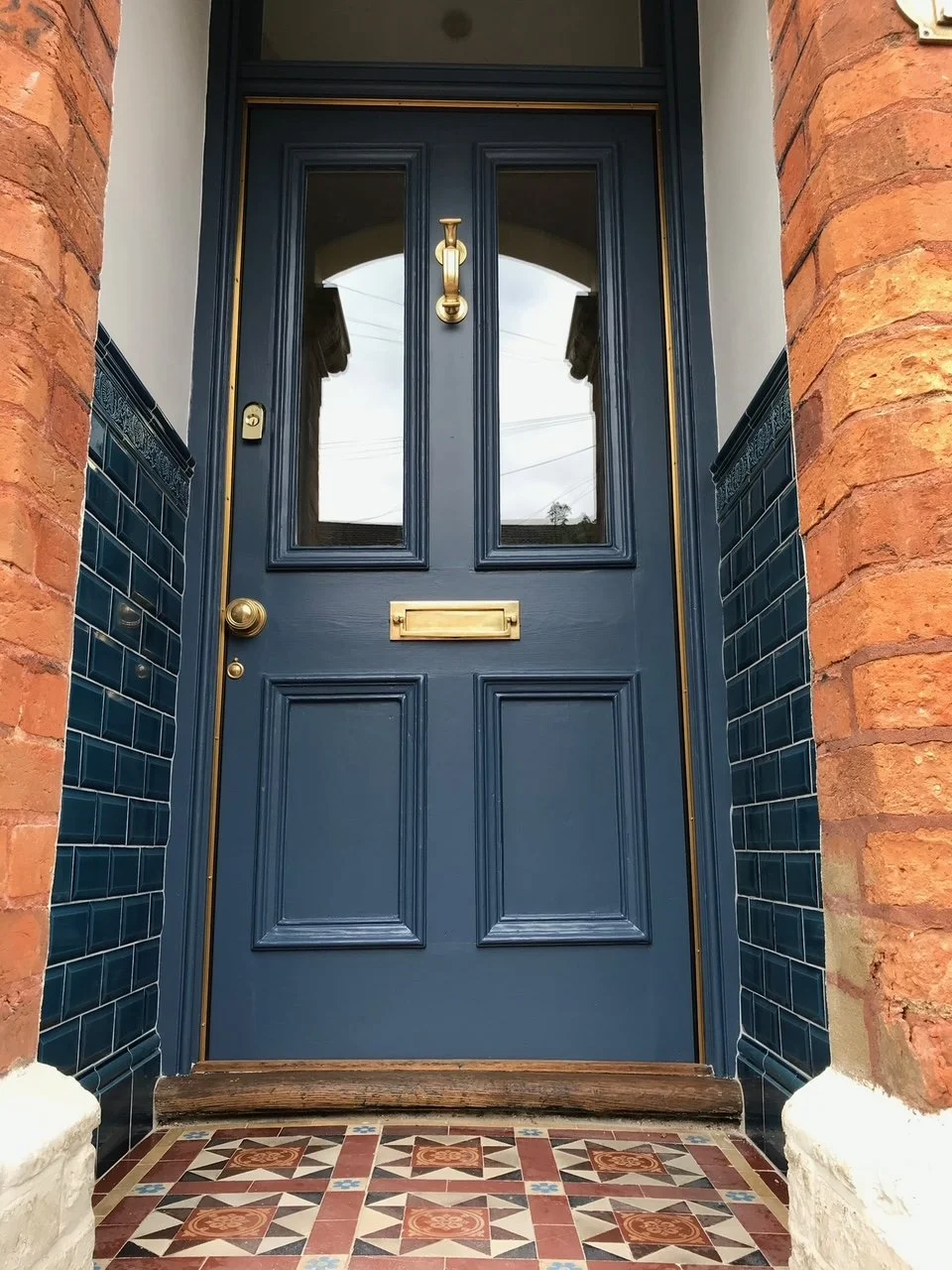 Close-up of a blue front door with a decorative tiled porch floor, restored by the Bedford Victorian Restoration team.