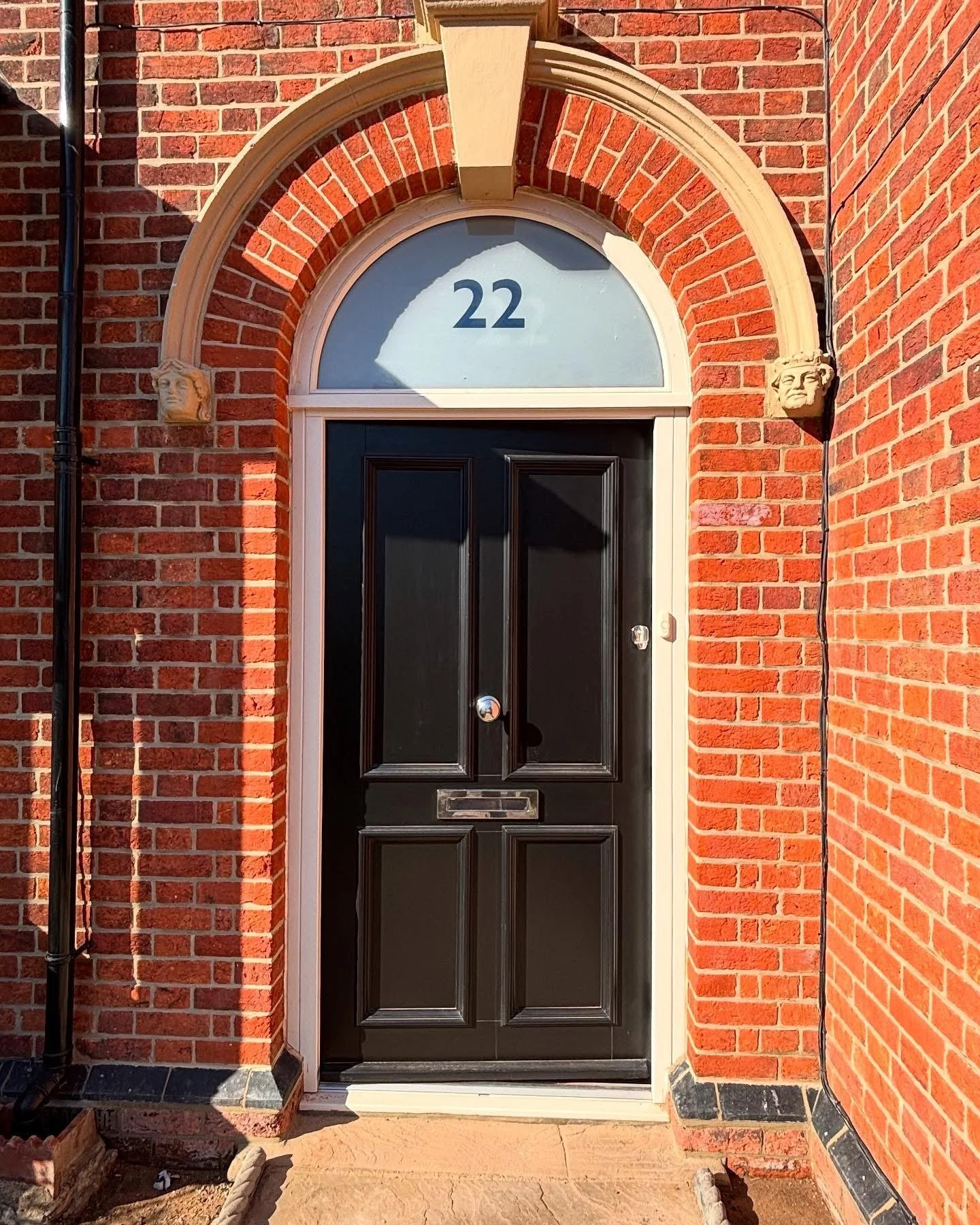 Front door of a Victorian house with a black door and a semicircular window above it, beautifully restored by the Bedford Victorian Restoration team.