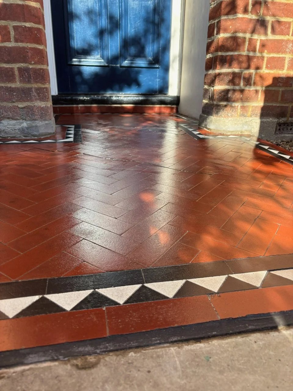 Close-up of a freshly restored Victorian, decorative front porch with an orange brick floor., work done by the Bedford Victorian Restoration Team.