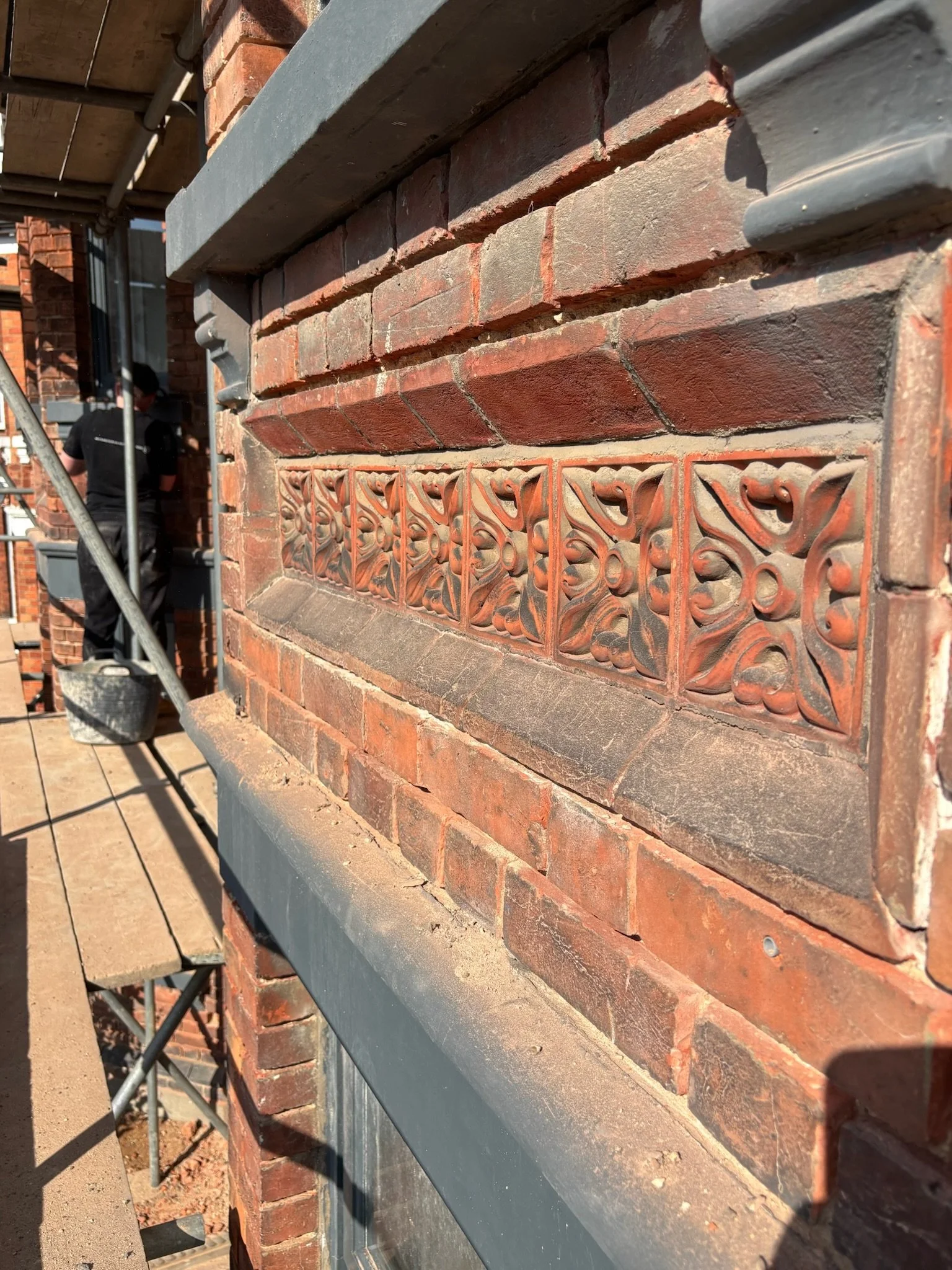 Close-up of a Victorian brick wall with decorative terracotta tiles.