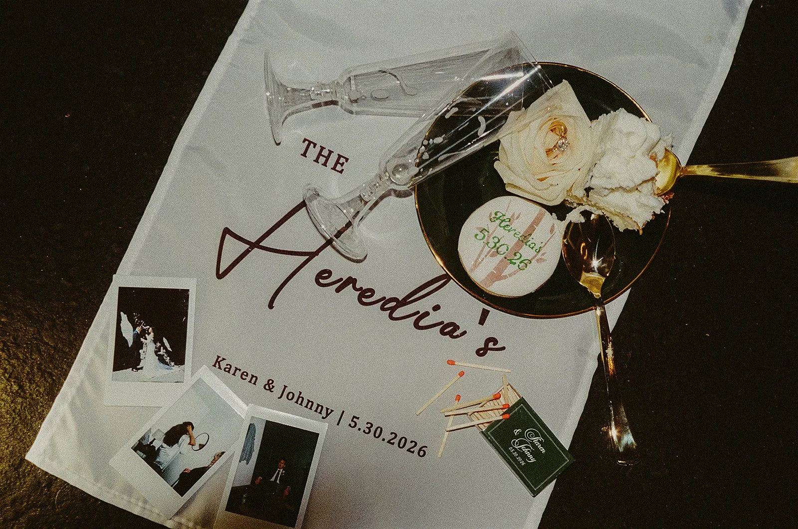 Wedding invitation with the words 'The Merendina's' and event details, a champagne flute, a black bowl with a white rose and whipped cream, and three Polaroid photos.