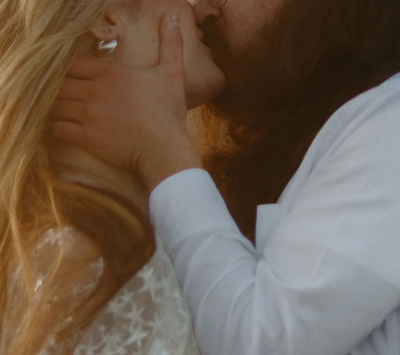 A couple sharing a kiss, with the man's hand gently holding the woman's face.
