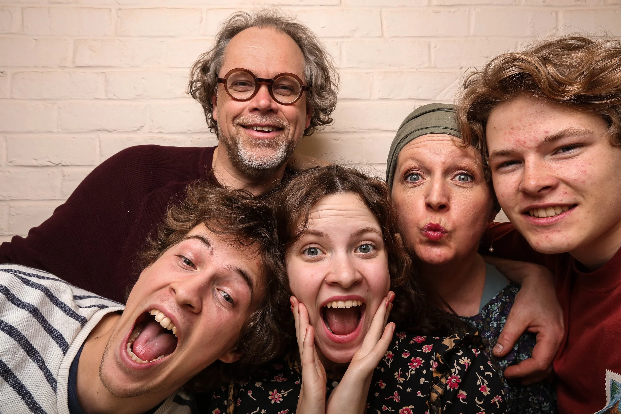 groupe de six personnes souriantes posant ensemble devant un mur en briques, expressions joyeuses et variées, photo pris avec notre photo booth.