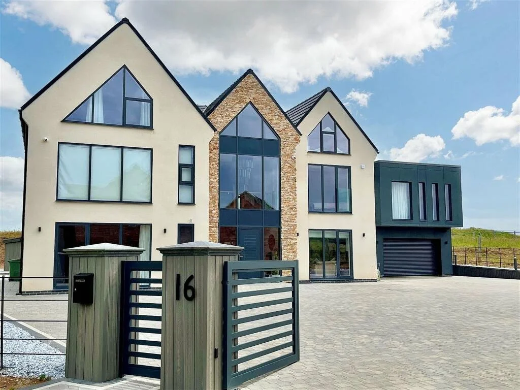 Modern multi-story house with large windows and a gated front entrance.