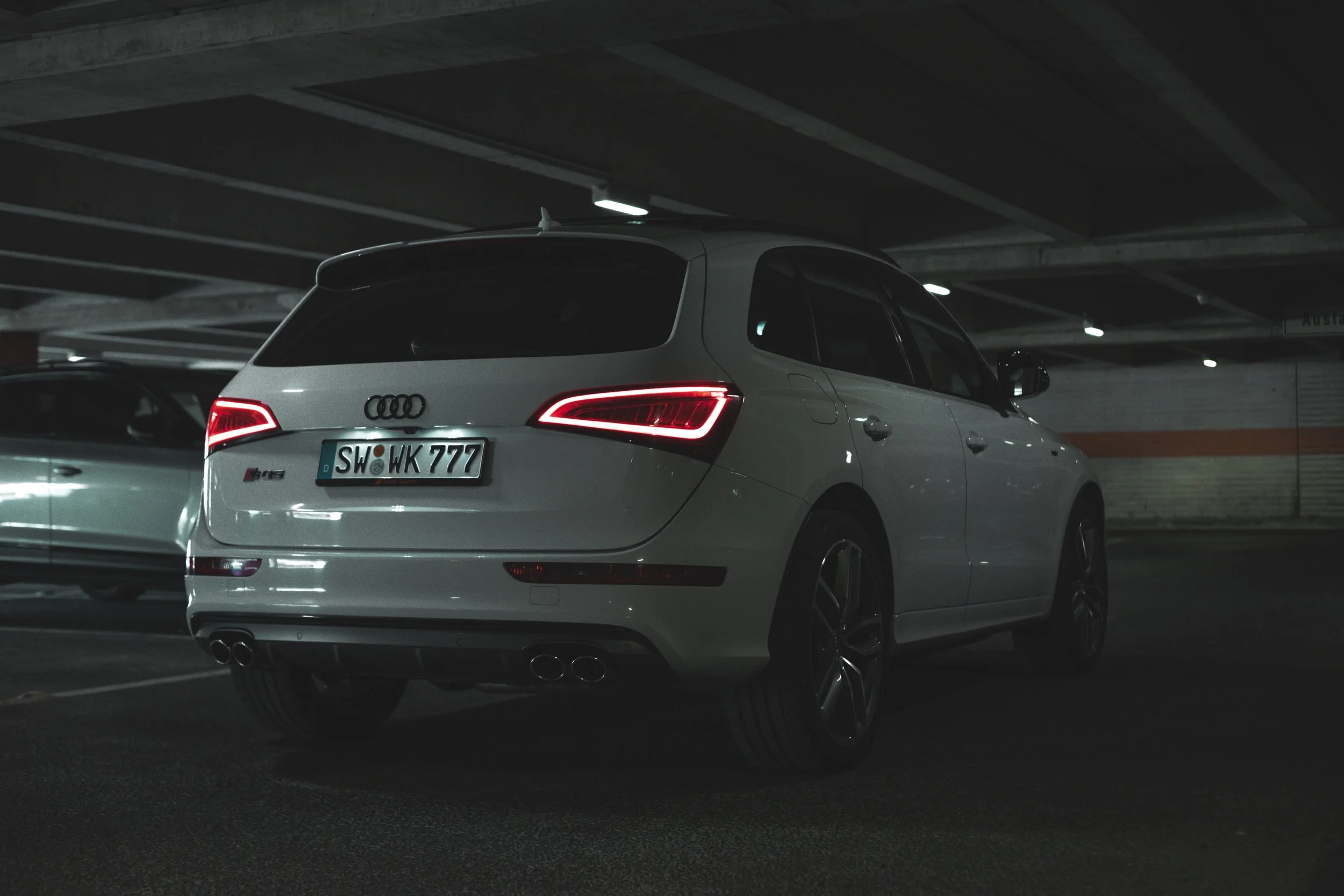 Ein weißer Audi SQ5im Untergrundparkhaus, gesehen von hinten, bei Nacht.