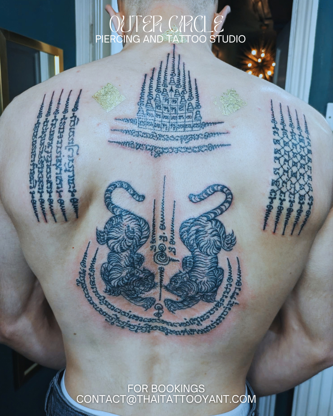 A traditional Sak Yant tattoo. Tattooed man's back with various Buddhist and spiritual symbols, including two tigers, script, and a stupa, at Outer Circle Piercing and Tattoo Studio. Contact email for bookings is contact@thaitattooyant.com.