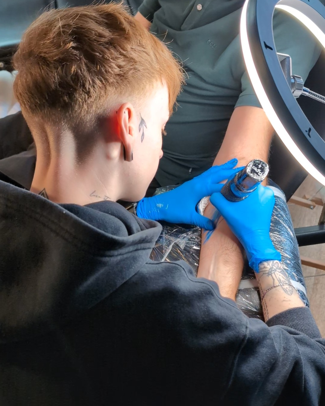 Chloe doing a tattoo on someone's arm