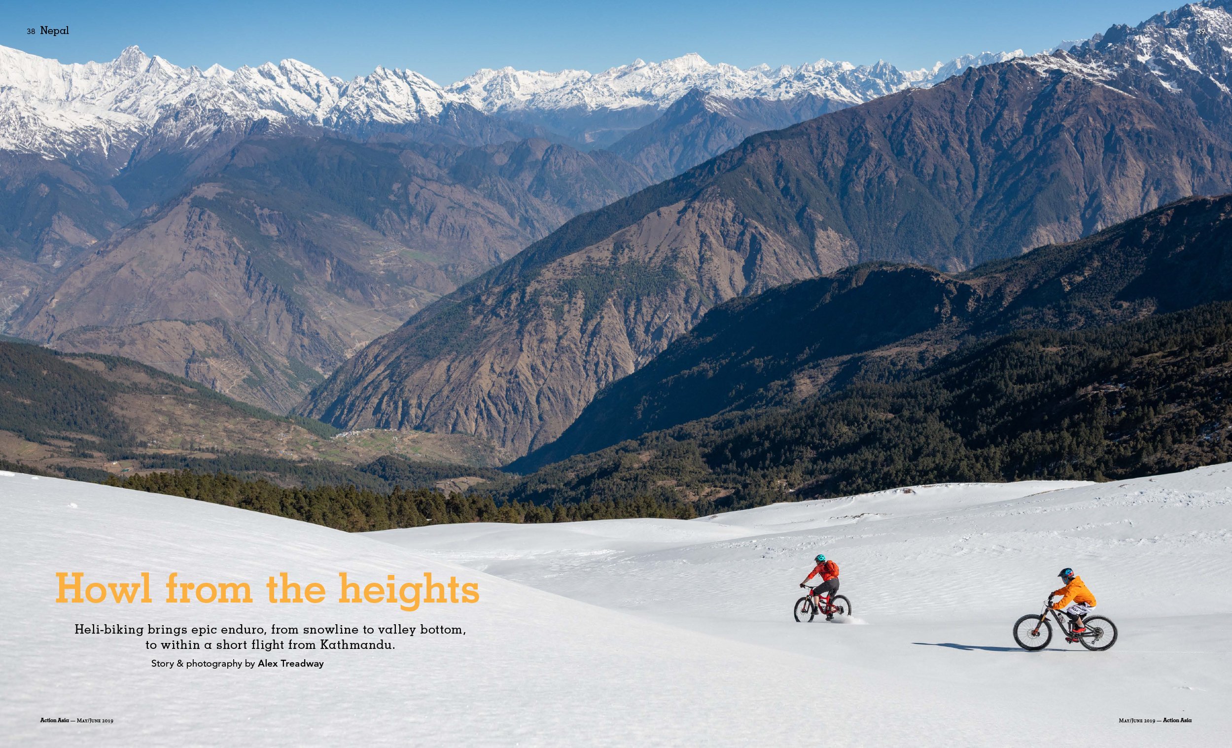 Mountains with snow-capped peaks and rugged terrain, with two people riding bicycles on a snow-covered landscape in the foreground.