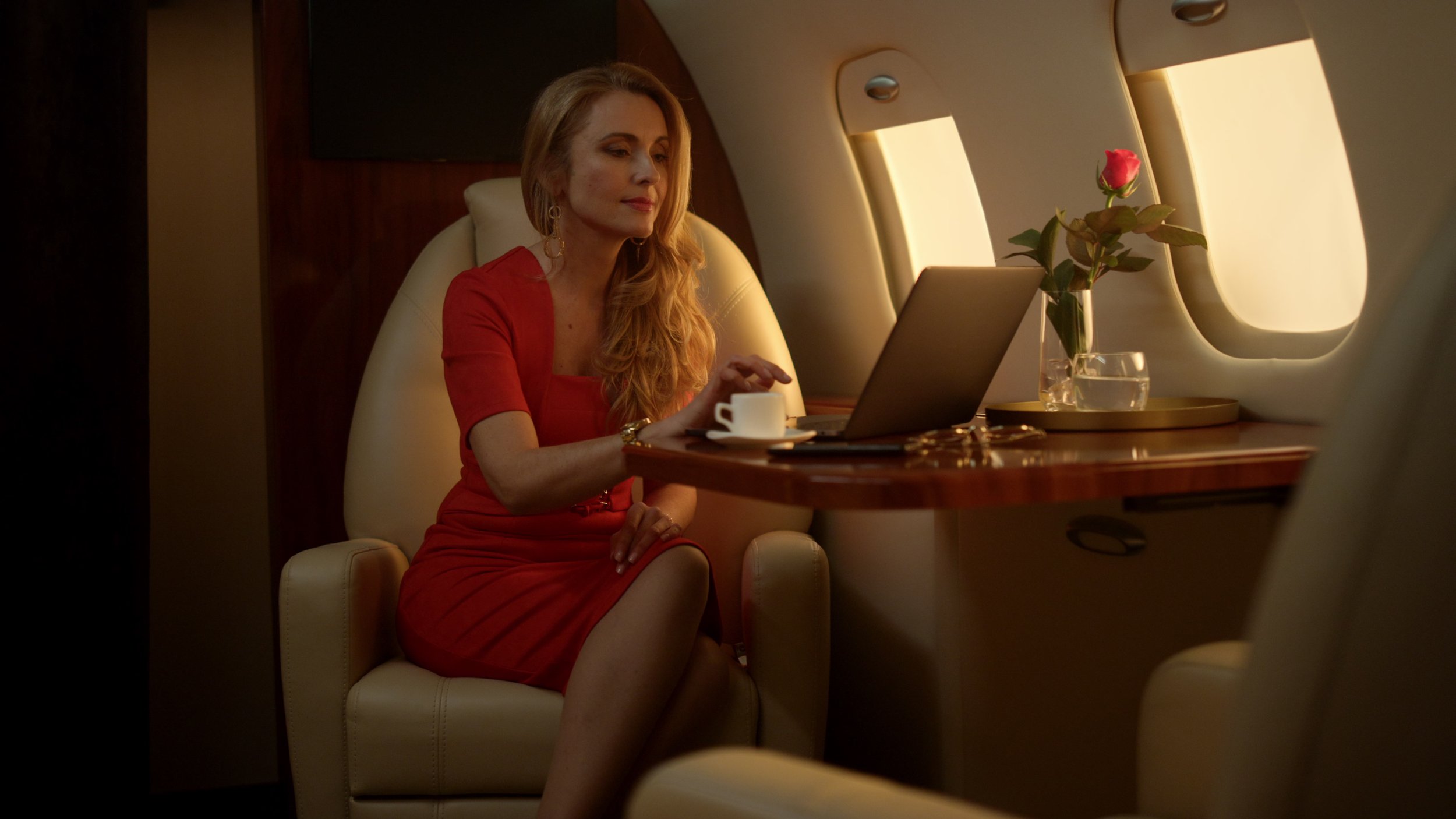 Woman in red dress working on a laptop on an airplane