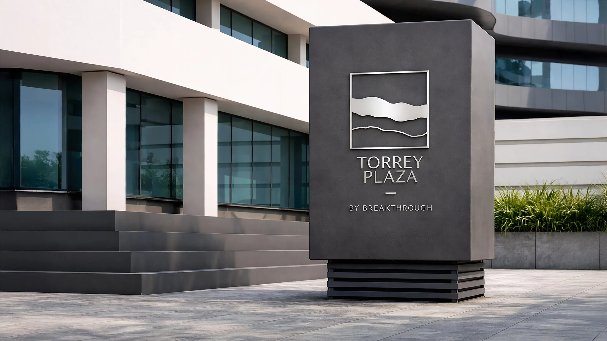 A modern building with large glass windows and a concrete facade. In front, a dark gray sign with the text 'Torrey Plaza by Breakthrough' and a minimalist logo featuring wavy lines.