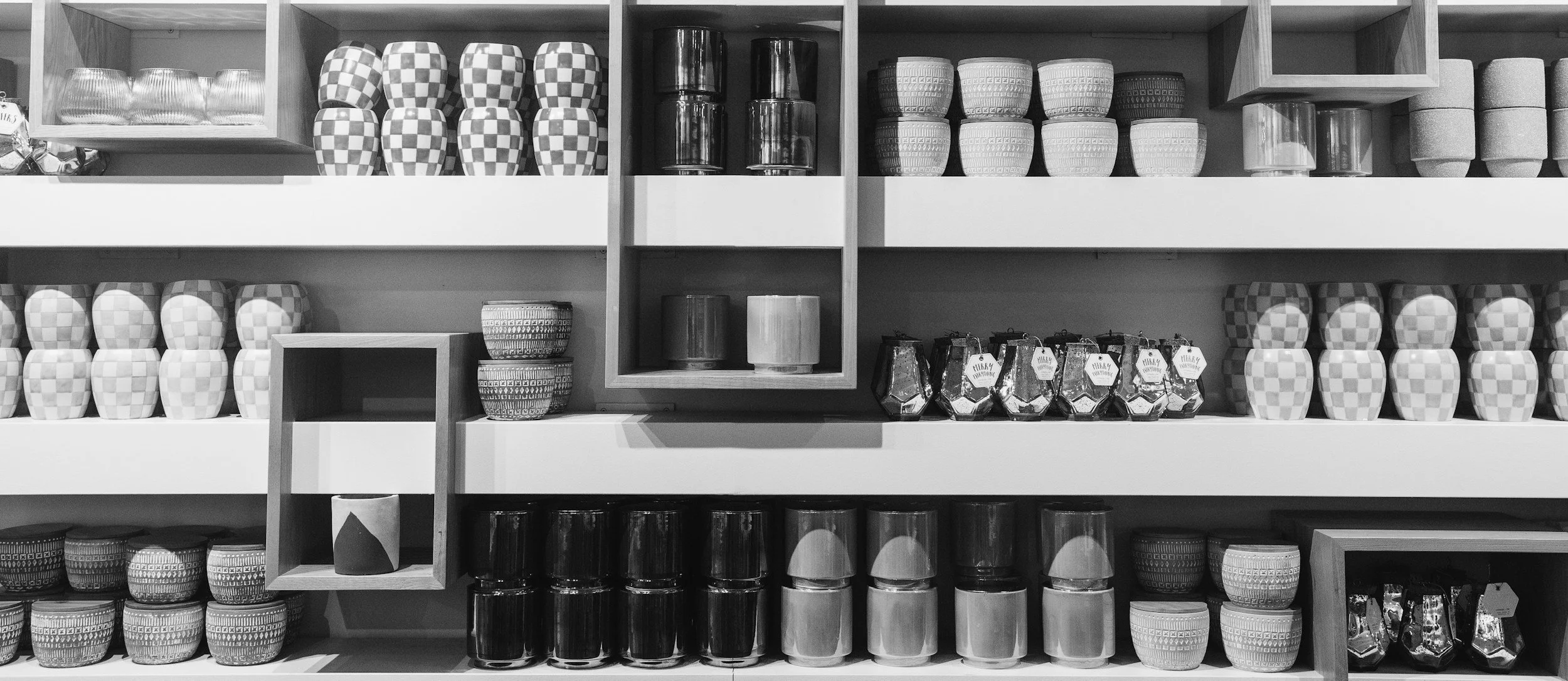 Black and white photo of a display shelf with various decorated pottery and cups.