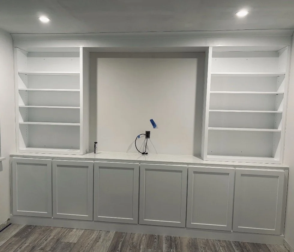 Empty white built-in shelves and cabinets in a room under construction or renovation.