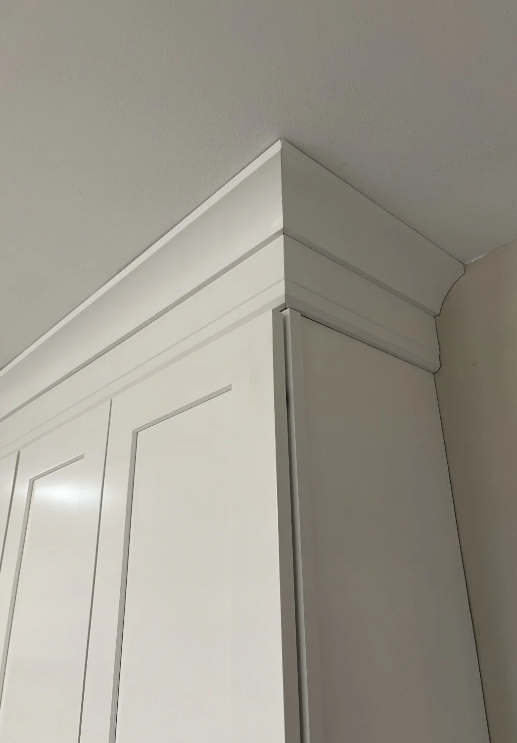 Close-up of a white door and crown molding at the ceiling corner of a room.